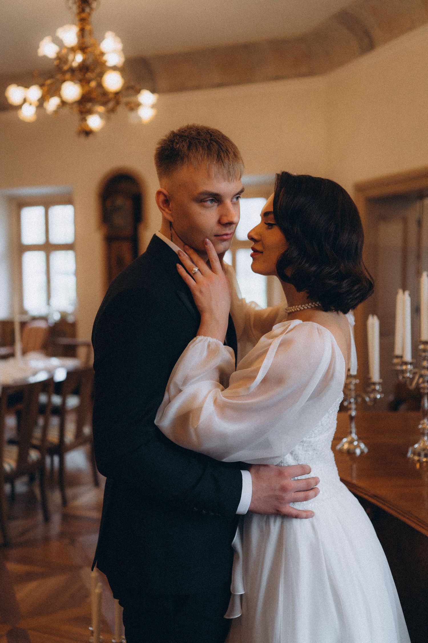 Bride gently touching the groom’s face as she looks at him while he poses for the camera during their wedding photoshoot.