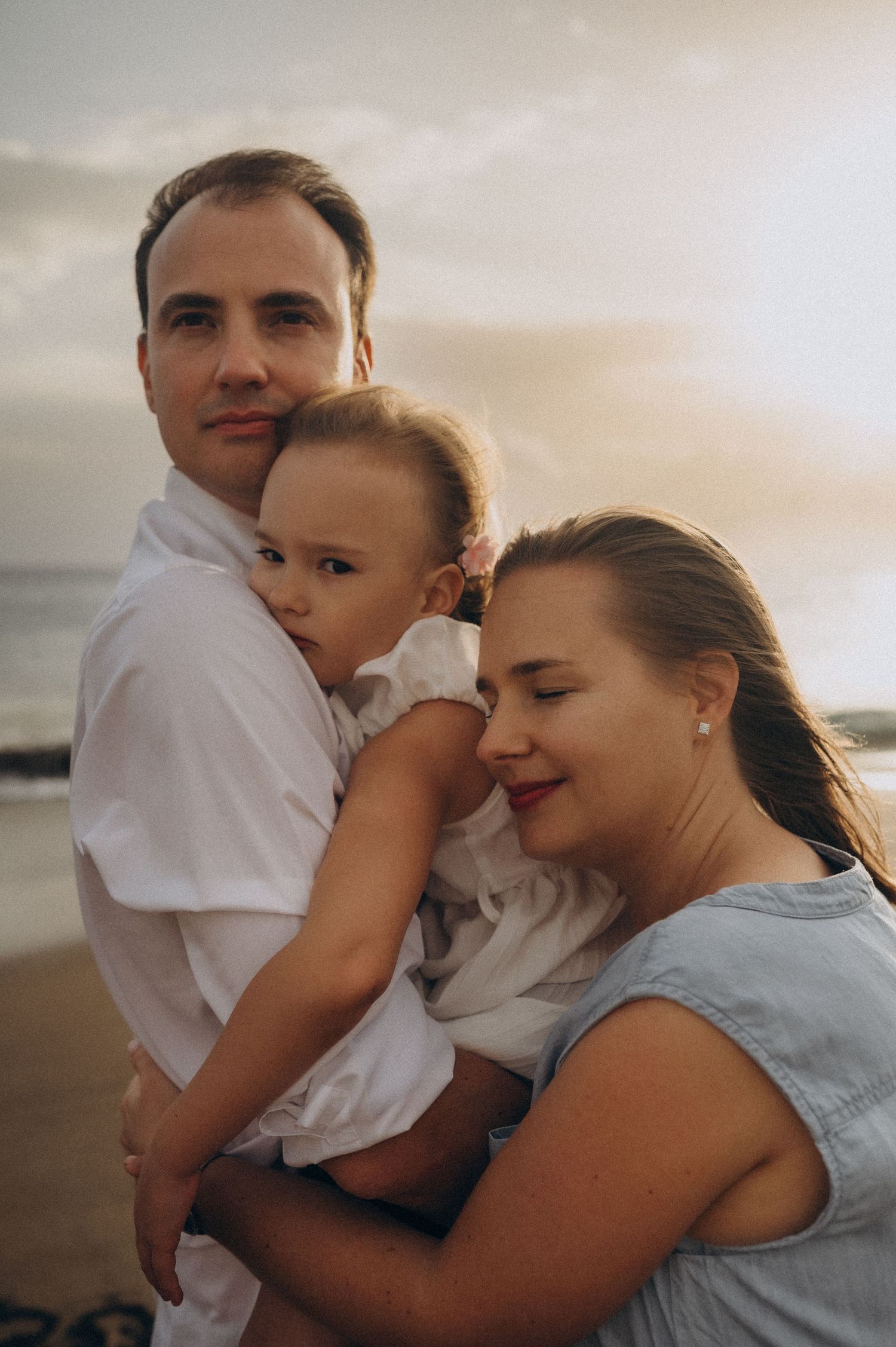 A family shares a tender moment together at sunset on the beach.