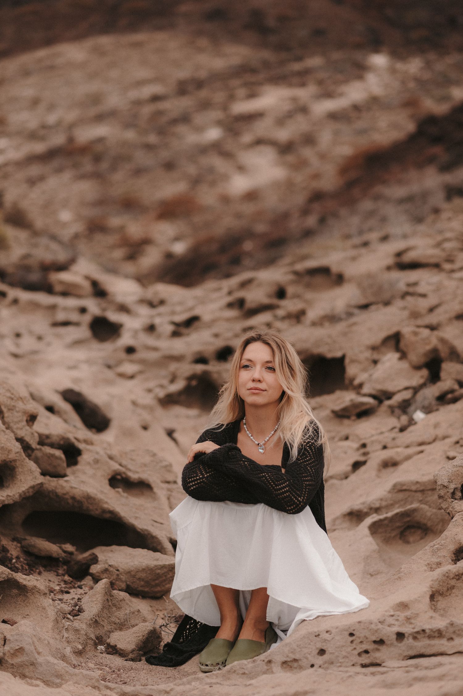 lose-up of a woman sitting on the rocks under Montaña Roja, enjoying a serene moment during a photoshoot in Tenerife