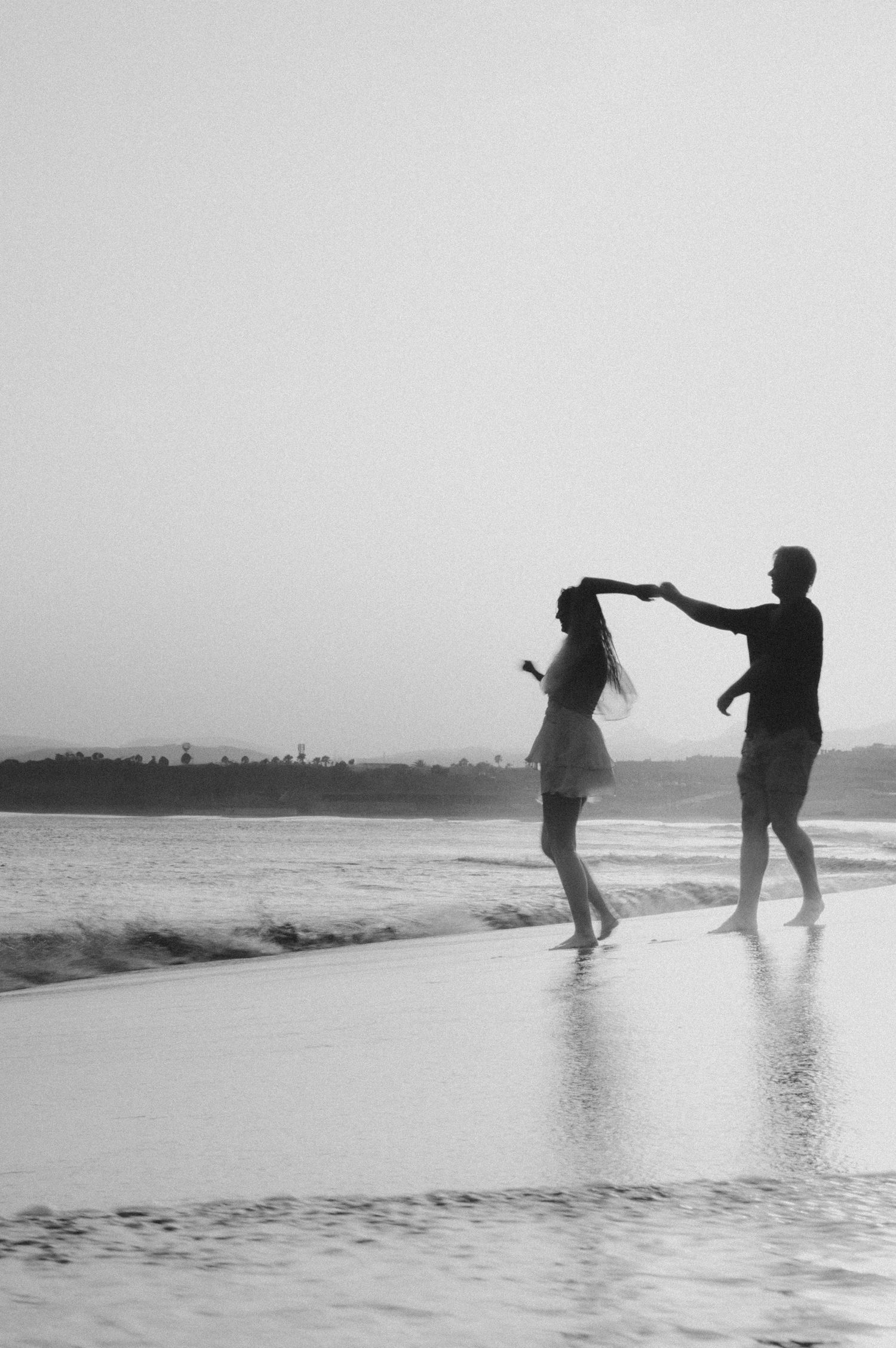 Young couple dancing and spinning barefoot on Playa Tejita sand