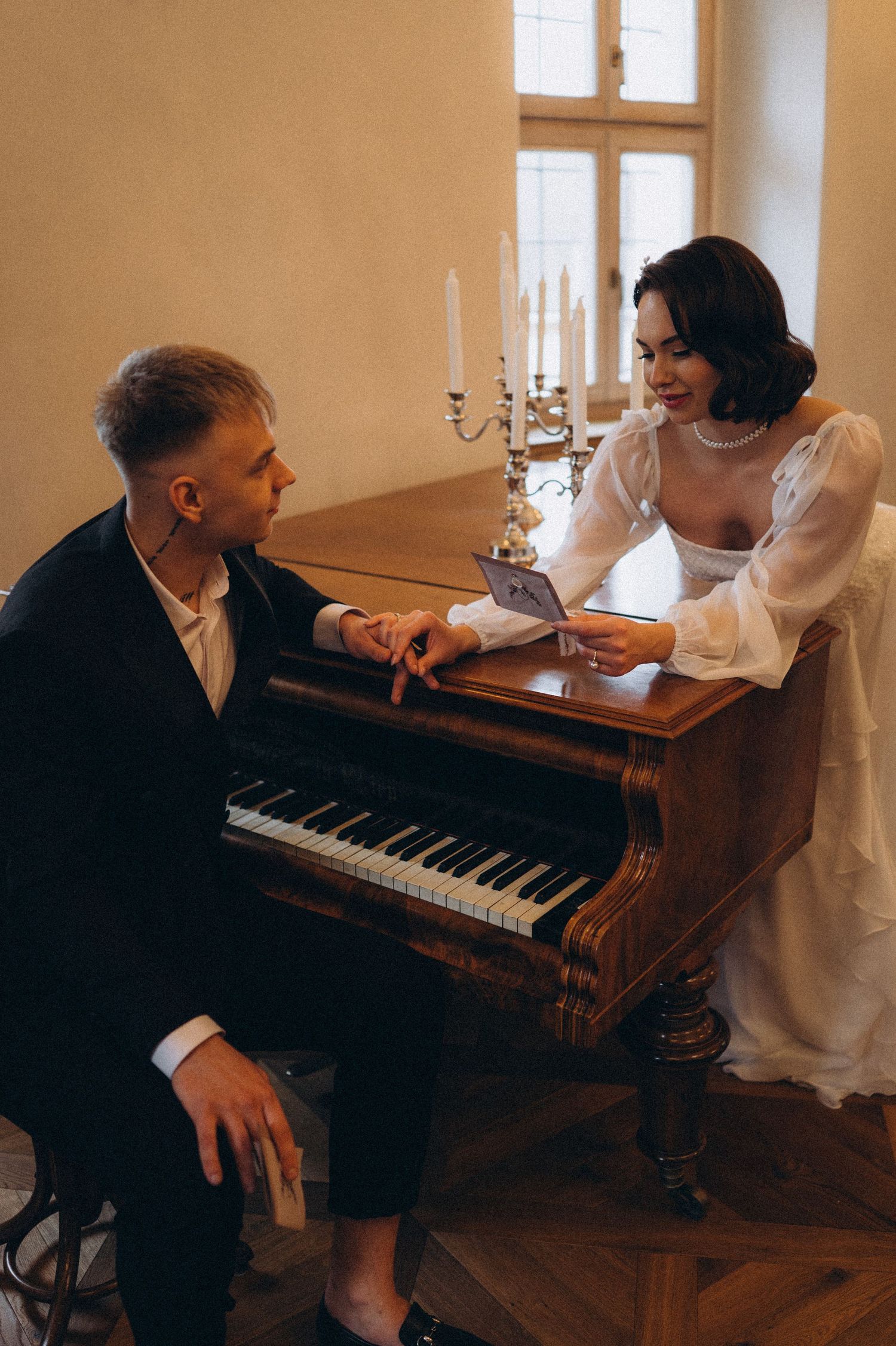 Fine art wedding portrait of the bride and groom at a piano, sharing a quiet and intimate moment.