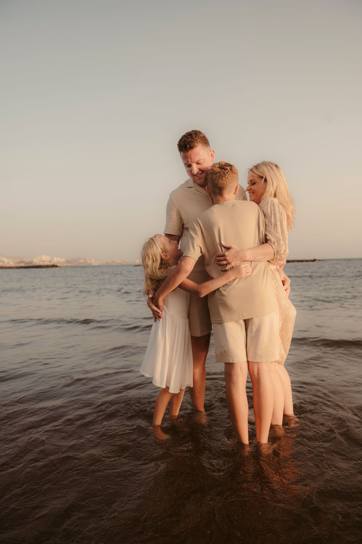 Family group hug by ocean during golden hour, Tenerife