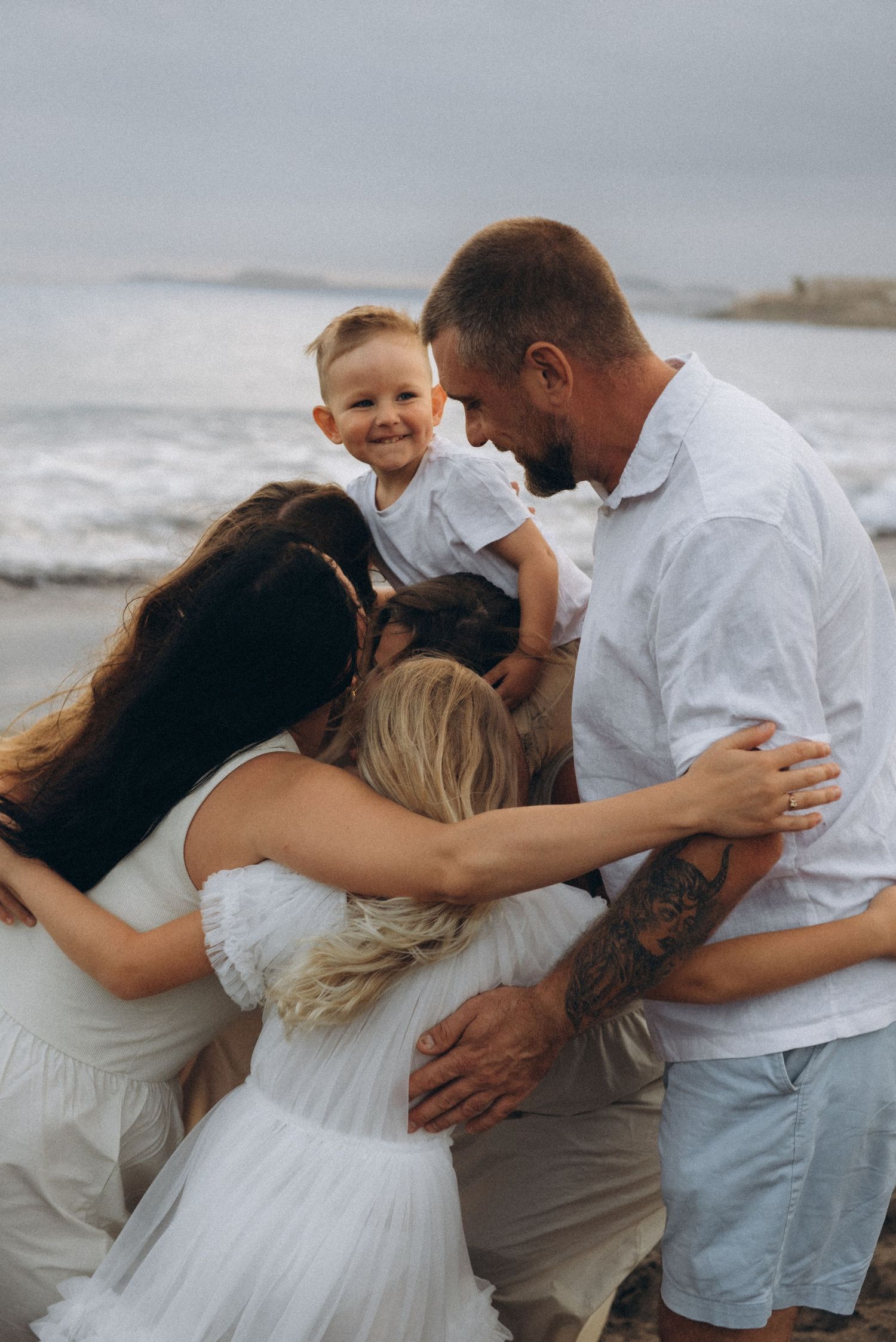 Family embrace on beach as everyone runs and hugs together, Playa La Tejita