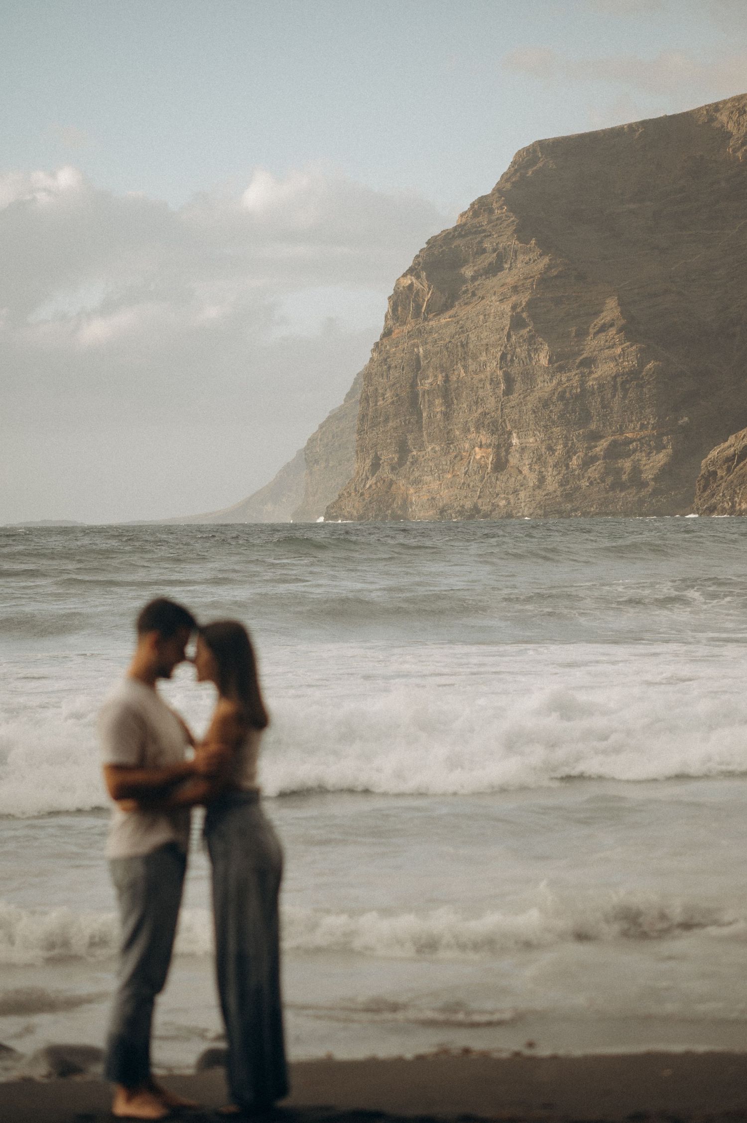 Couple sharing tender embrace as woman looks at him with love, Playa de Los Guíos, Tenerife
