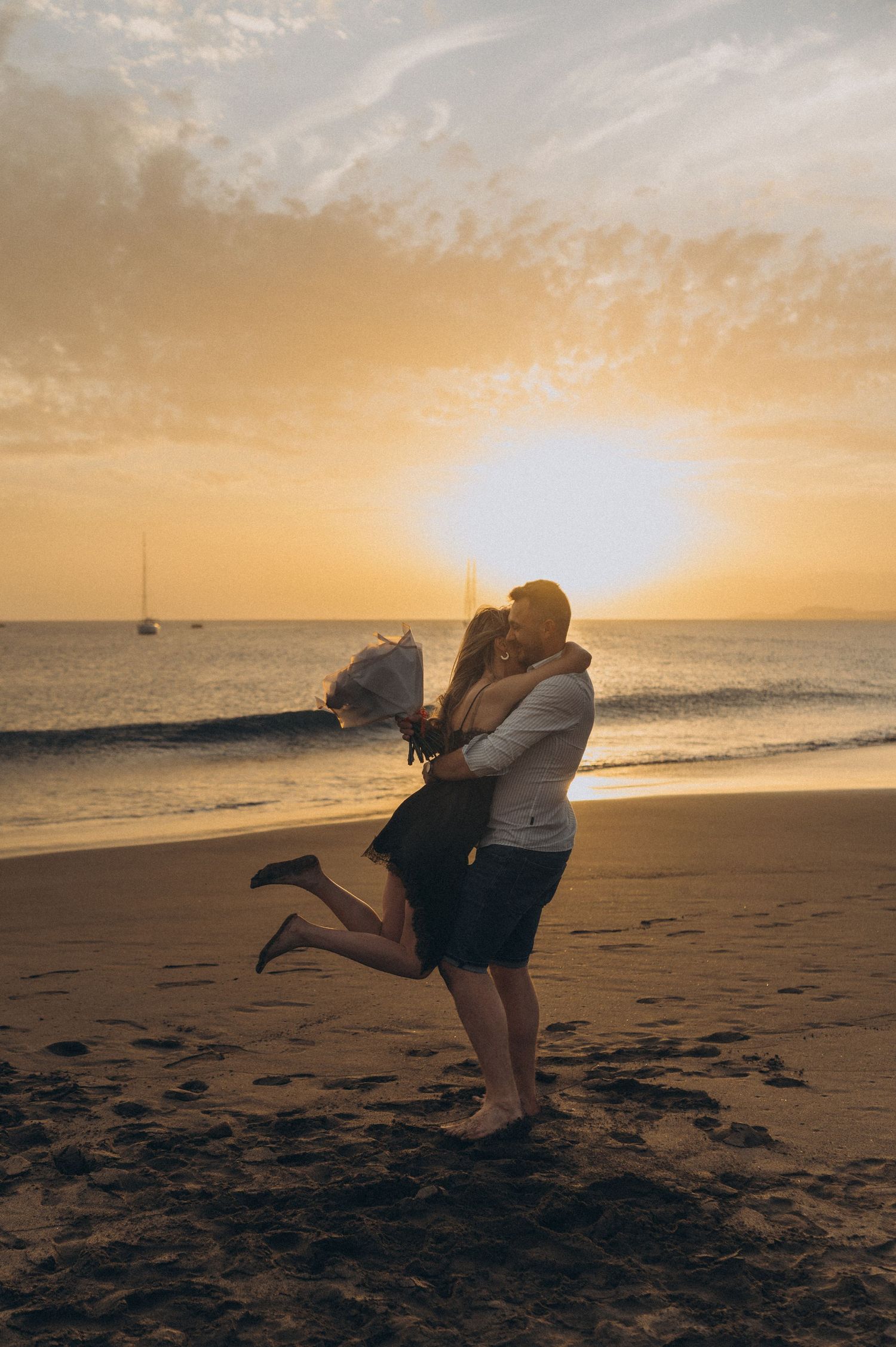 Woman jumping into partner’s arms as they spin at sunset, Playa de La Tejita, Tenerife