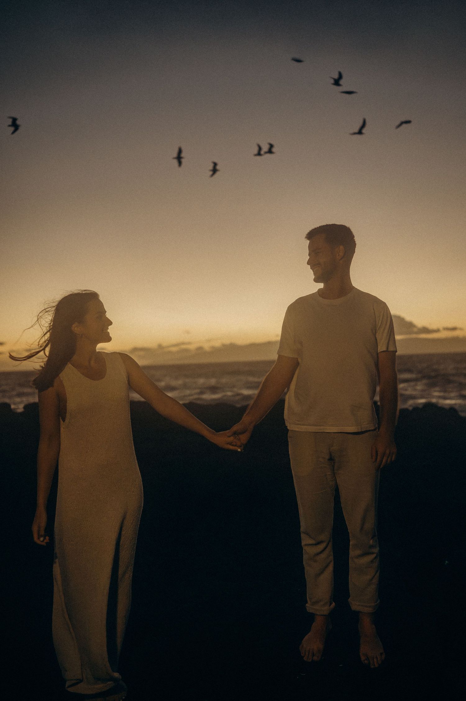 Intimate couple gazing at each other on beach at night with gentle lights, south Tenerife
