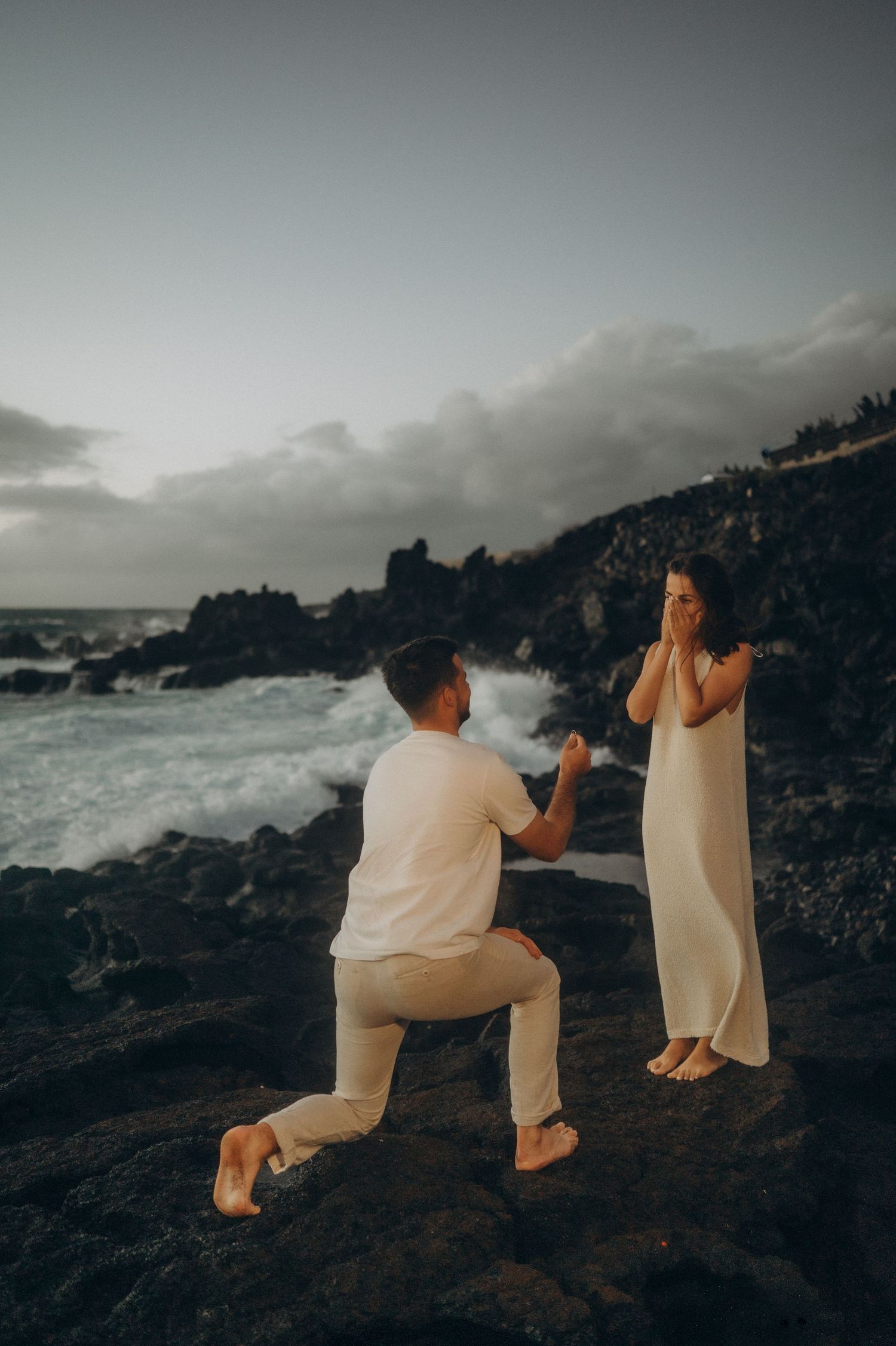 Man proposing to his beloved on volcanic rocks by the ocean in Tenerife during romantic moment