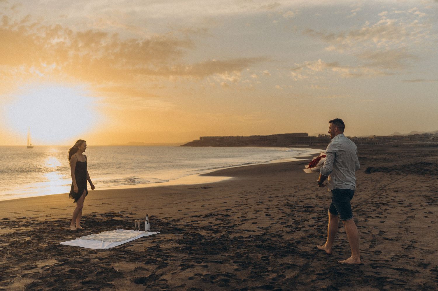 Romantic moment of couple toasting champagne after proposal on Playa de La Tejita, Tenerife