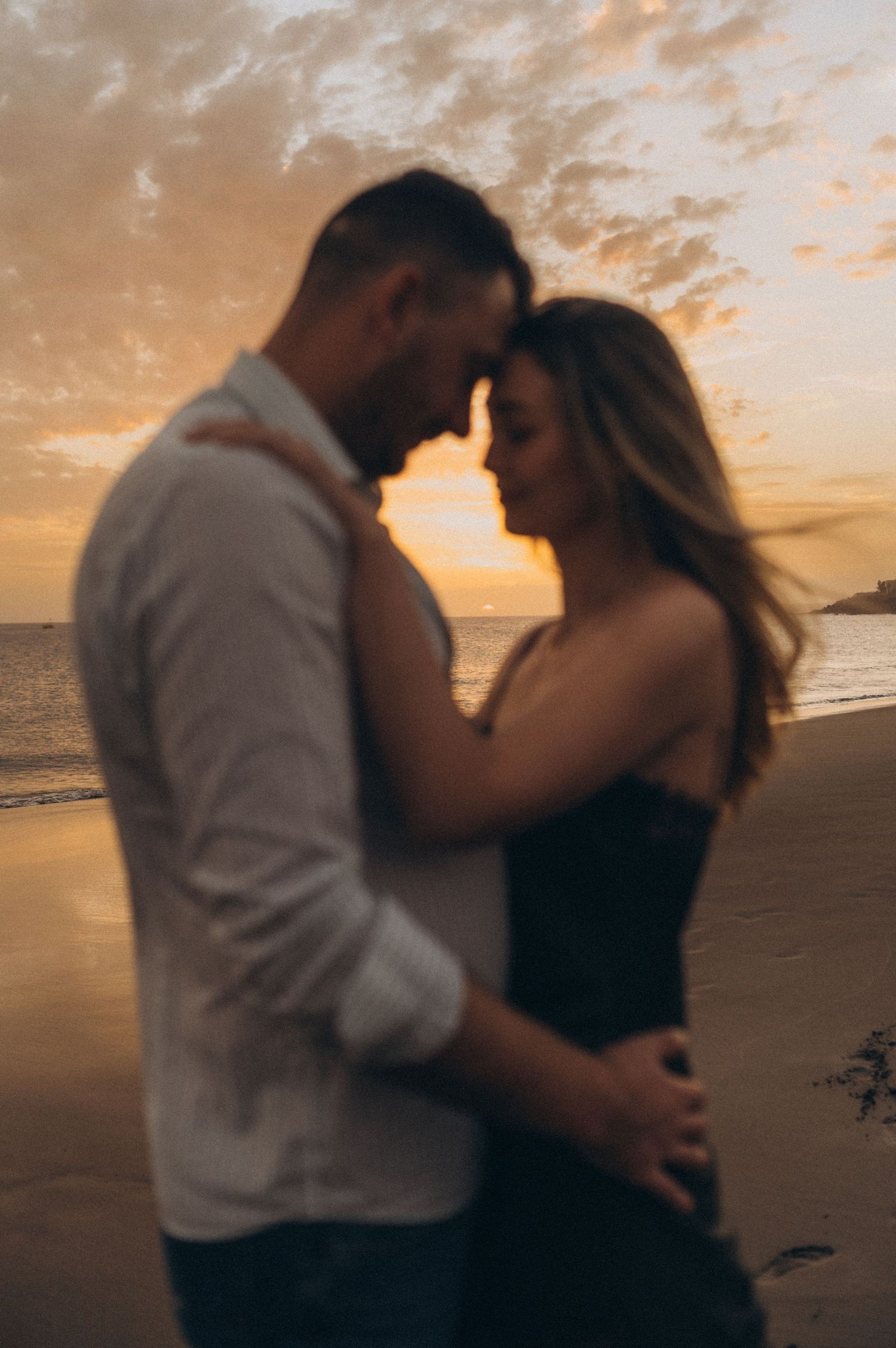 Romantic couple looking at each other during sunset on Playa de La Tejita, Tenerife