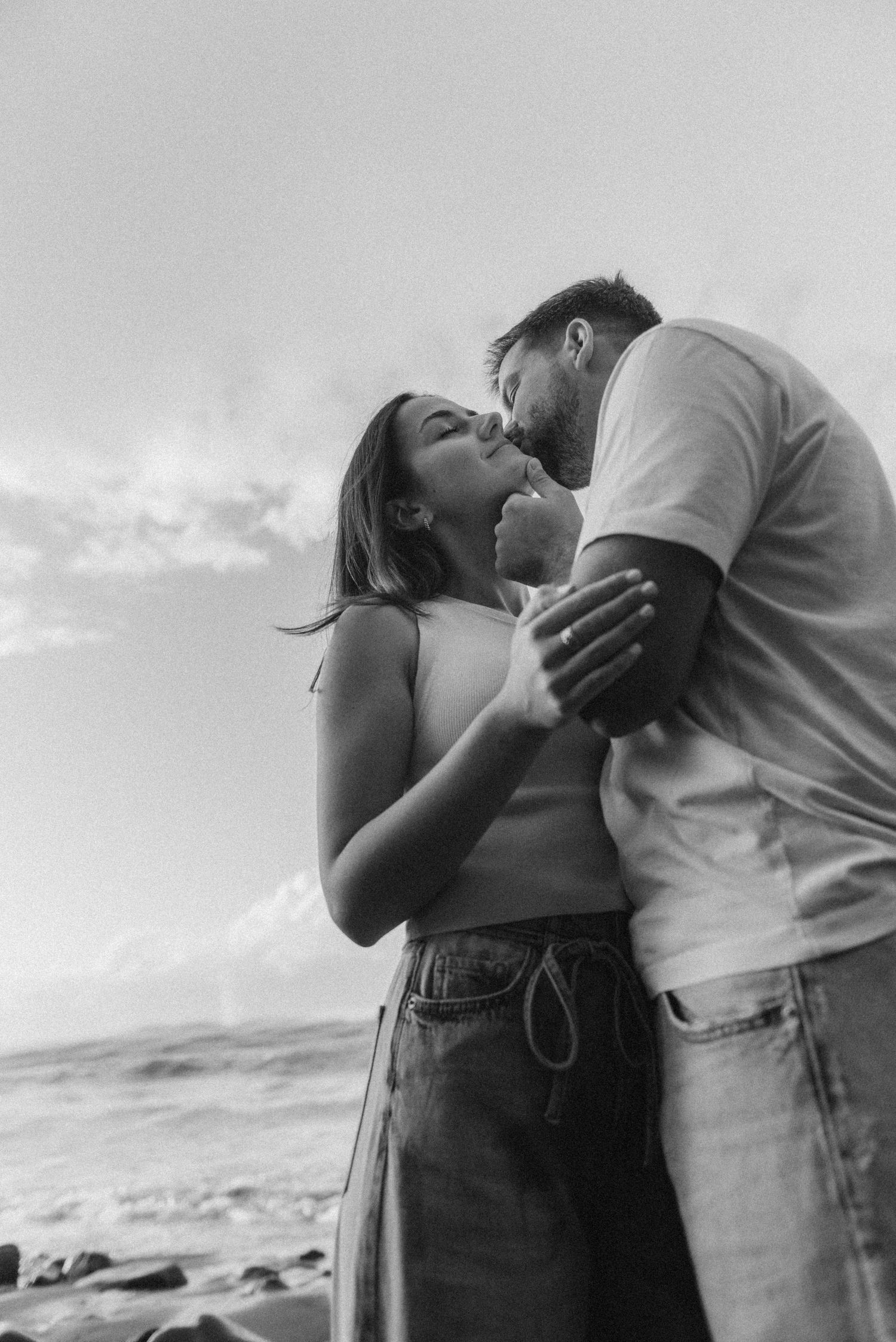 Young couple sharing intimate kiss on neck on Playa de Los Guíos beach by the ocean, Tenerife