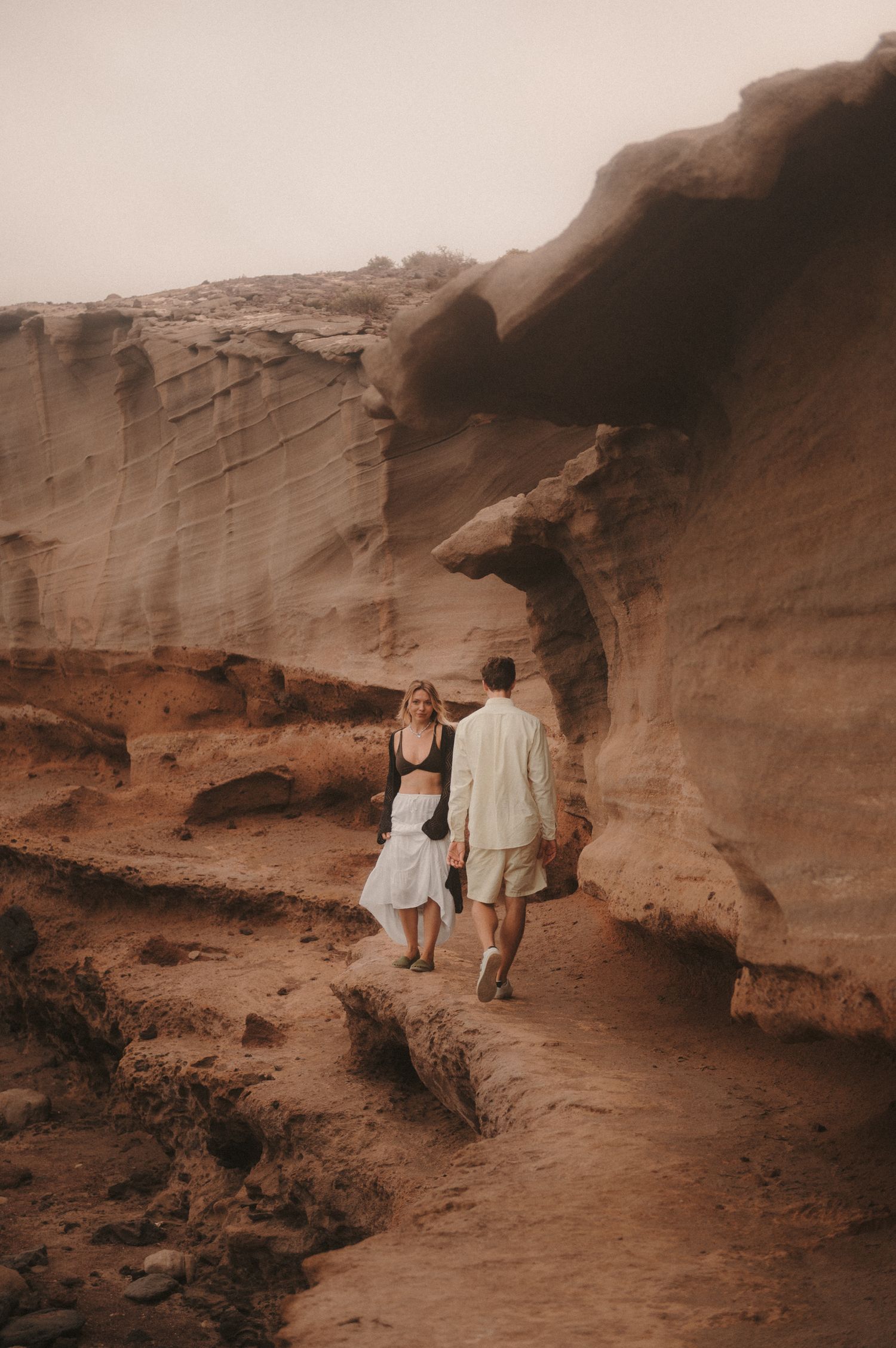Loving couple walking under the large cliffs of Montaña Roja during a romantic photoshoot in Tenerife