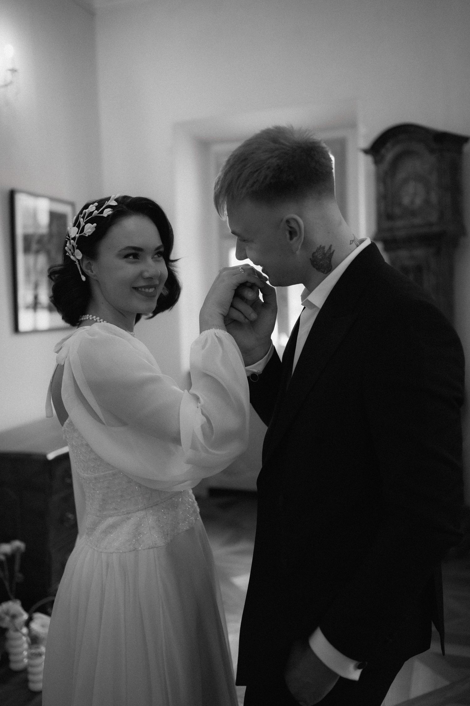 Black and white portrait of the groom kissing the bride’s hand showing her wedding ring.