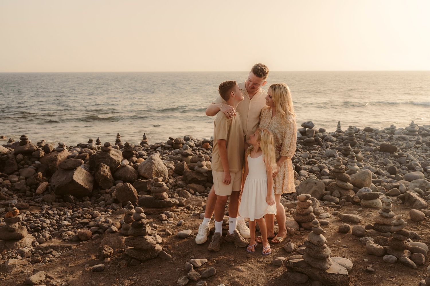 arents facing each other with children standing in front, ocean and sunset behind, Playa del Duque