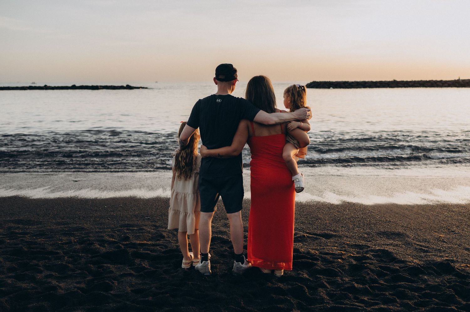 Family enjoying a peaceful sunset while looking at the ocean on Playa del Duque beach