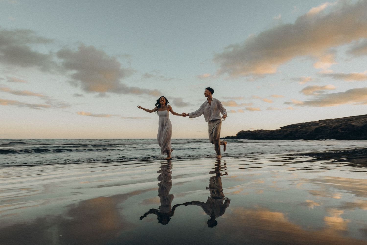 Two silhouettes dance together on a reflective beach Playa Montana Pelada at sunset with cloudy skies and ocean waves in the background.