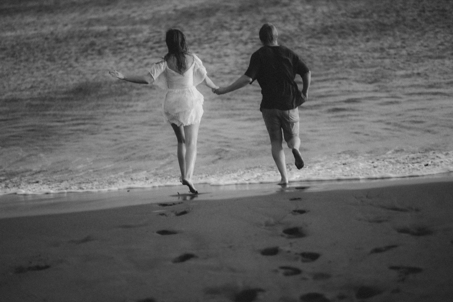 Couple running barefoot along the shore of Playa Tejita, Tenerife photoshoot