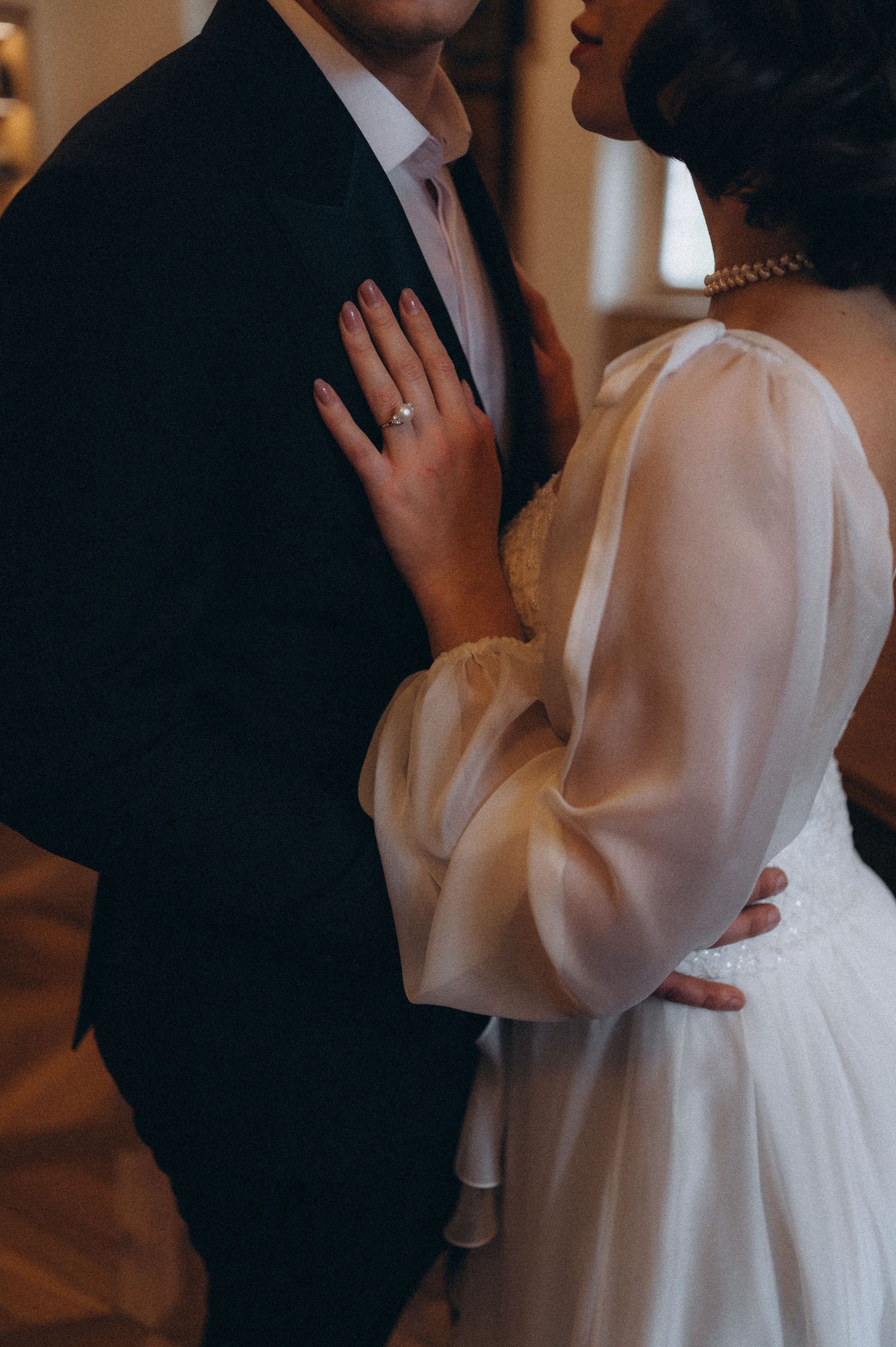 Bride standing close to the groom with her hand resting on his chest during their wedding photoshoot.