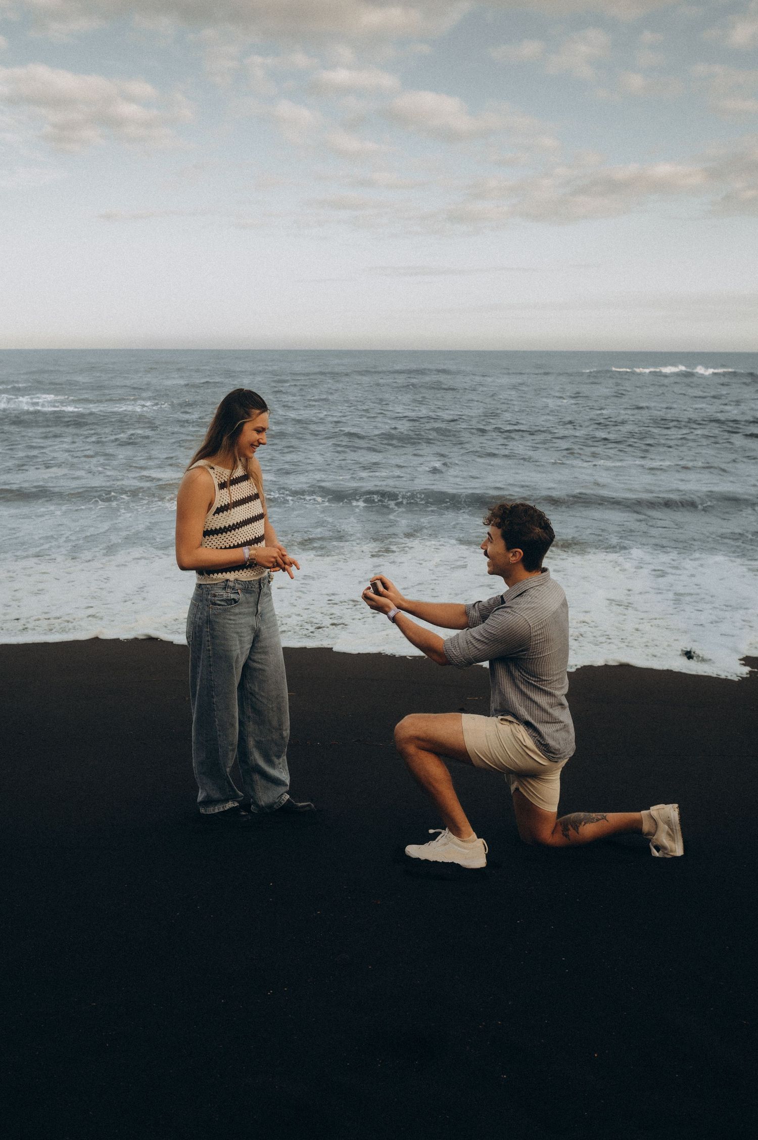 Surprise proposal in Puerto de la Cruz, Tenerife on rocky coastal cliffs with a romantic kiss at sunset.