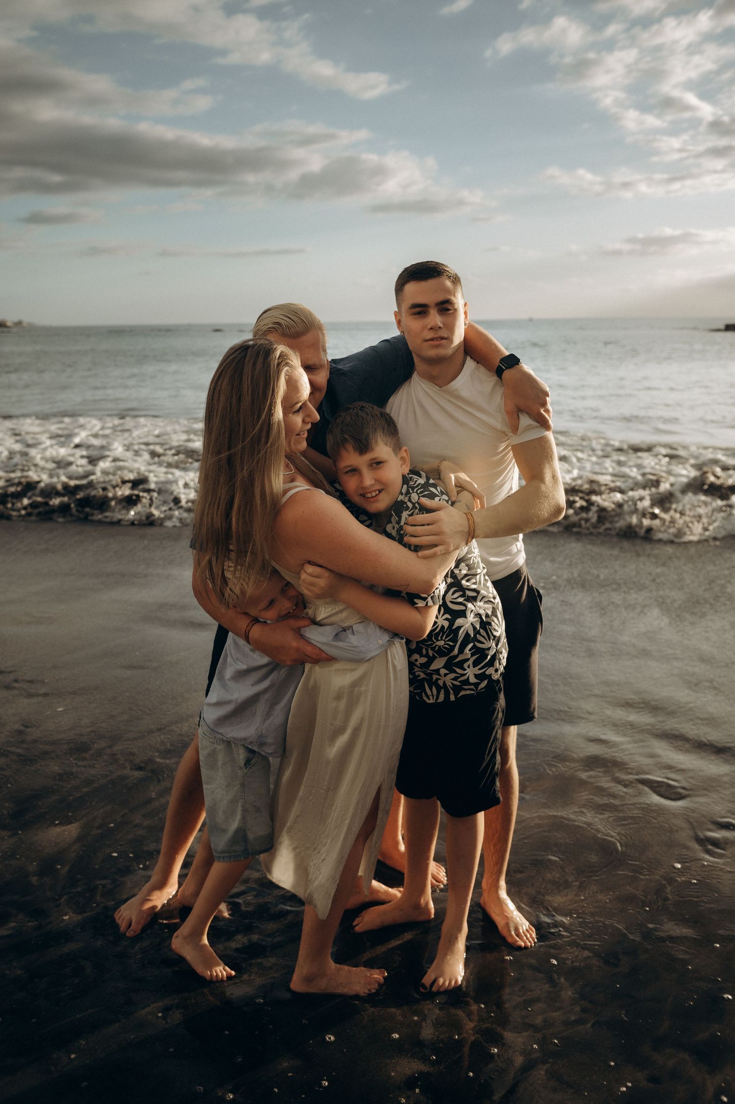 Family group hug on black sand beach, Playa Fañabé Tenerife