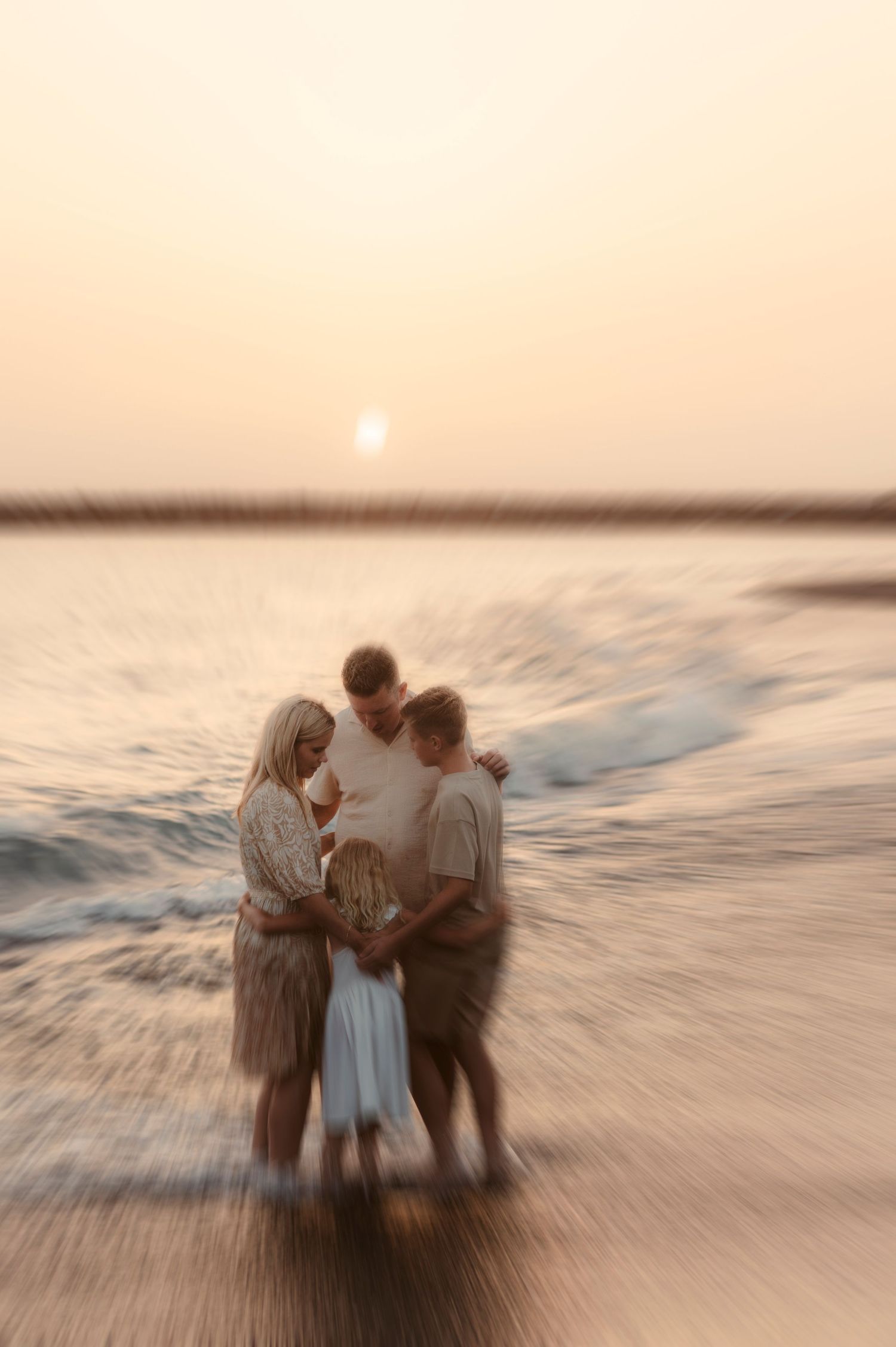 Parents and children in group hug by sea during sunset, Playa del Duque Tenerife