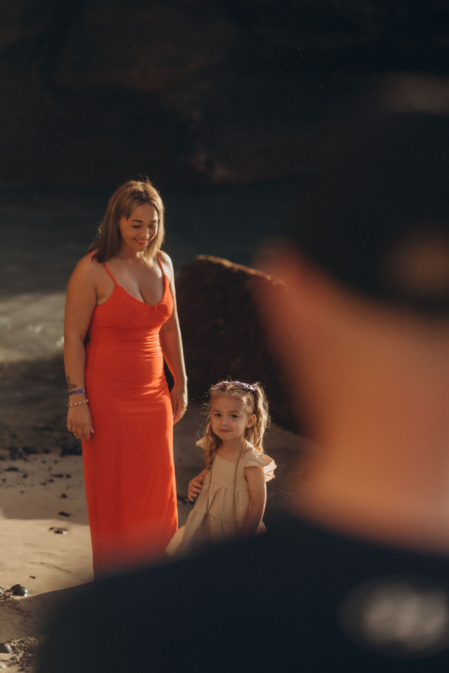 Father slightly visible from behind as his wife and daughters smile over his shoulder