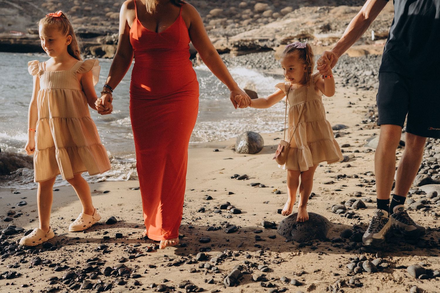 Family of four holding hands walking along the ocean at Playa Morteros