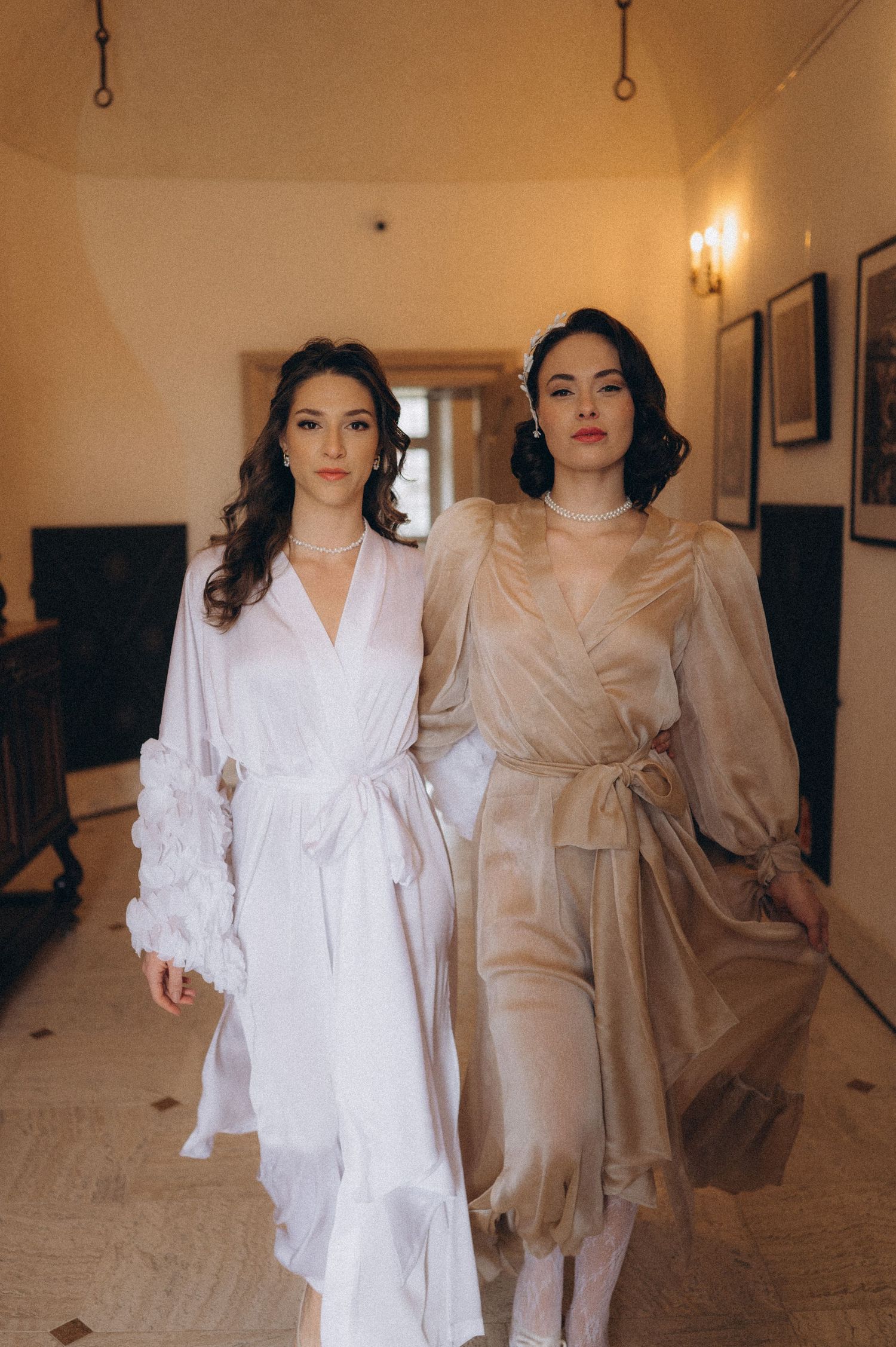Two brides walking together through an elegant hallway in a wedding editorial photoshoot.