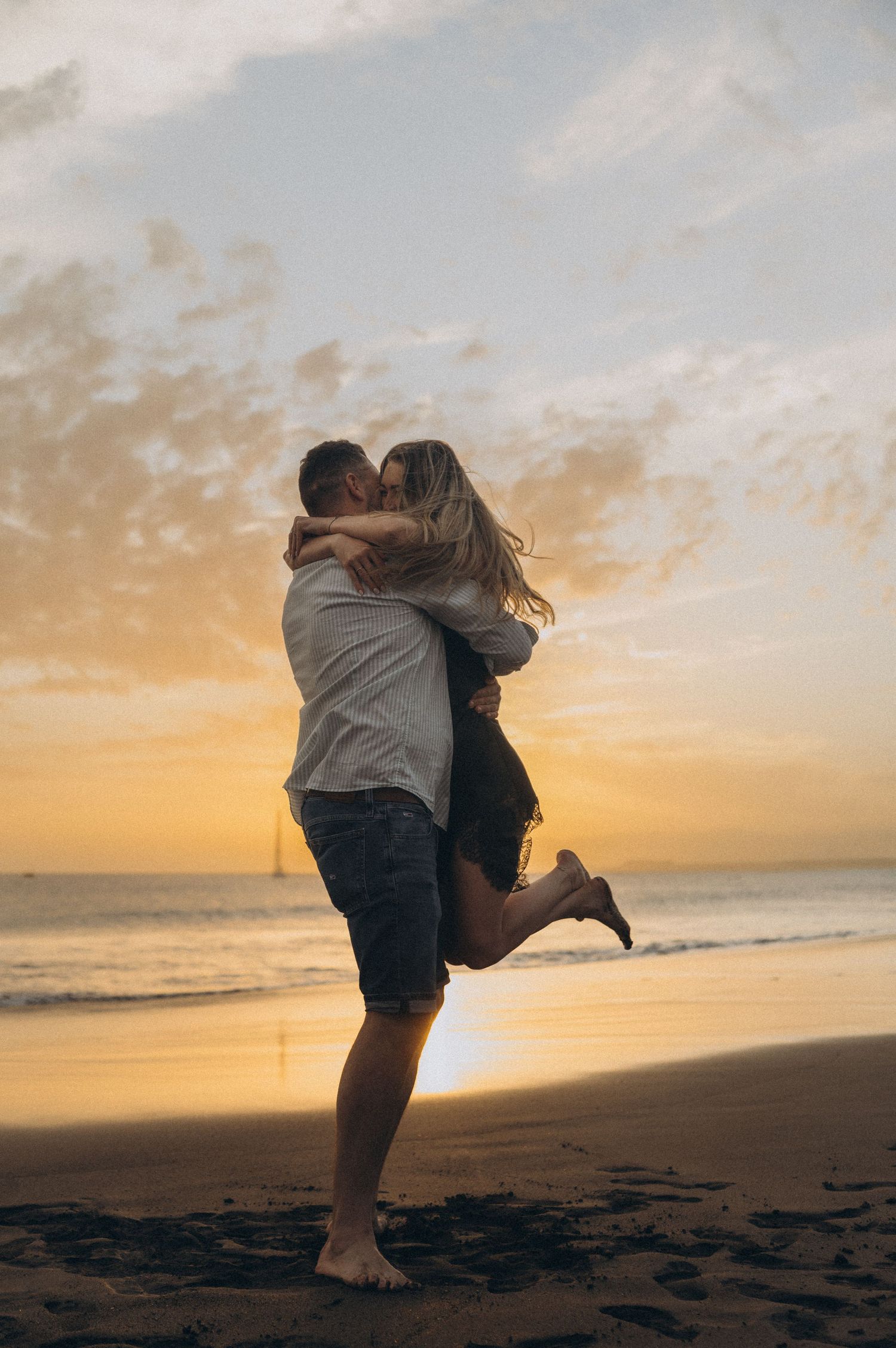 Romantic couple in hug with man kissing her on Playa de La Tejita, Montaña Roja, Tenerife