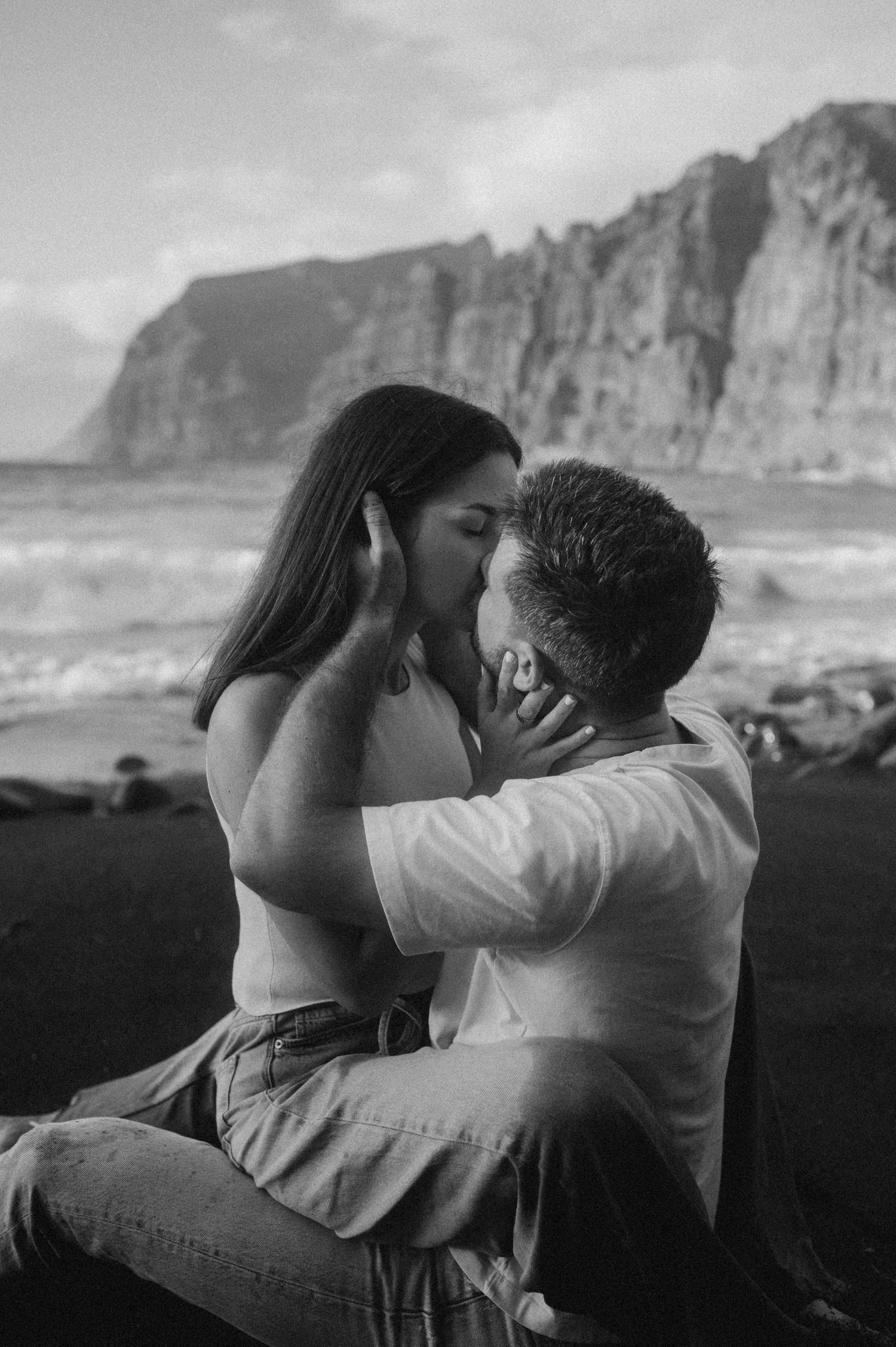 Couple enjoying intimate moment seated by Los Gigantes cliffs on Playa de Los Guíos, Tenerife