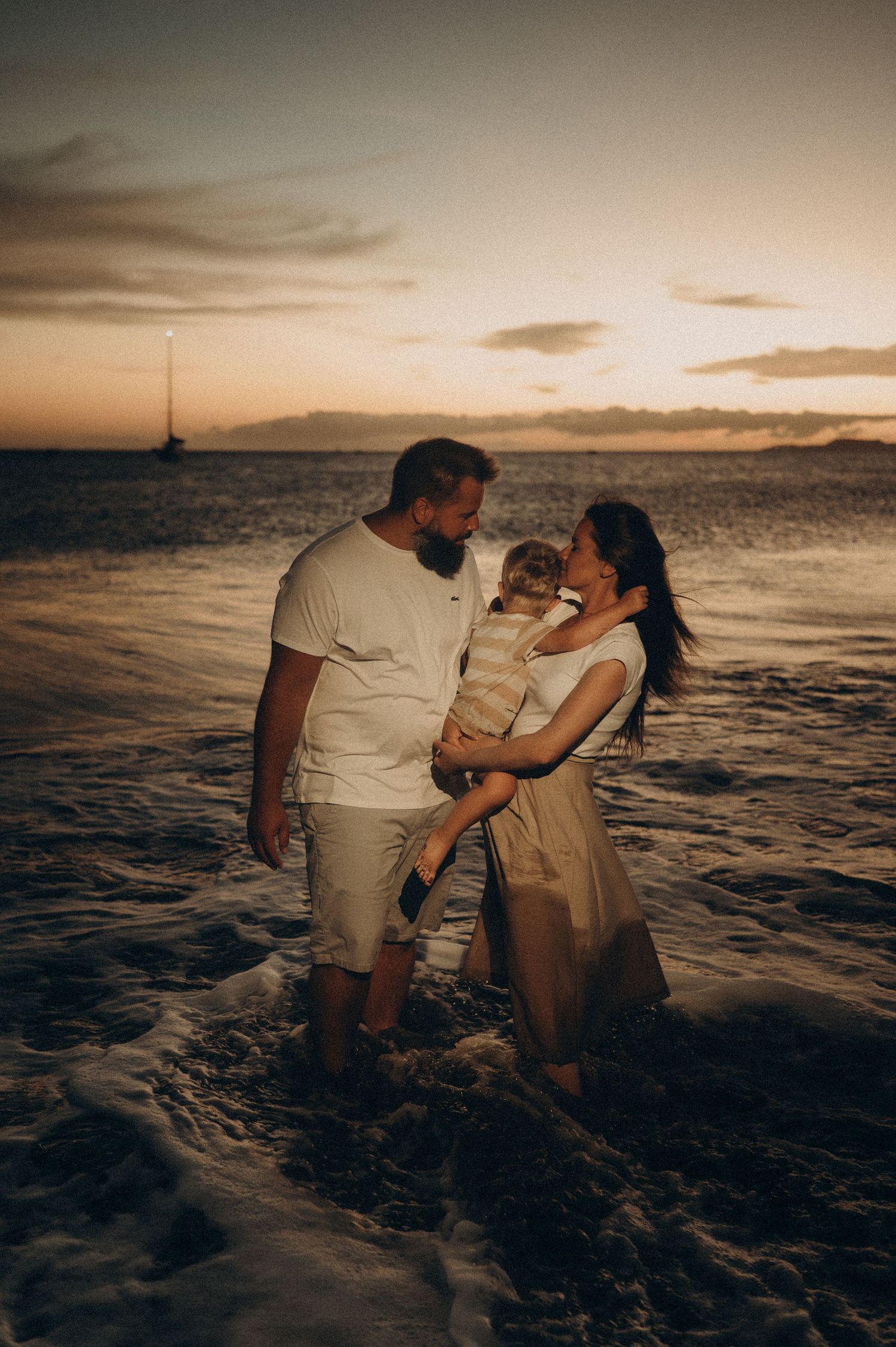 Family standing in the ocean after sunset enjoying a special moment at Playa La Tejita, Tenerife