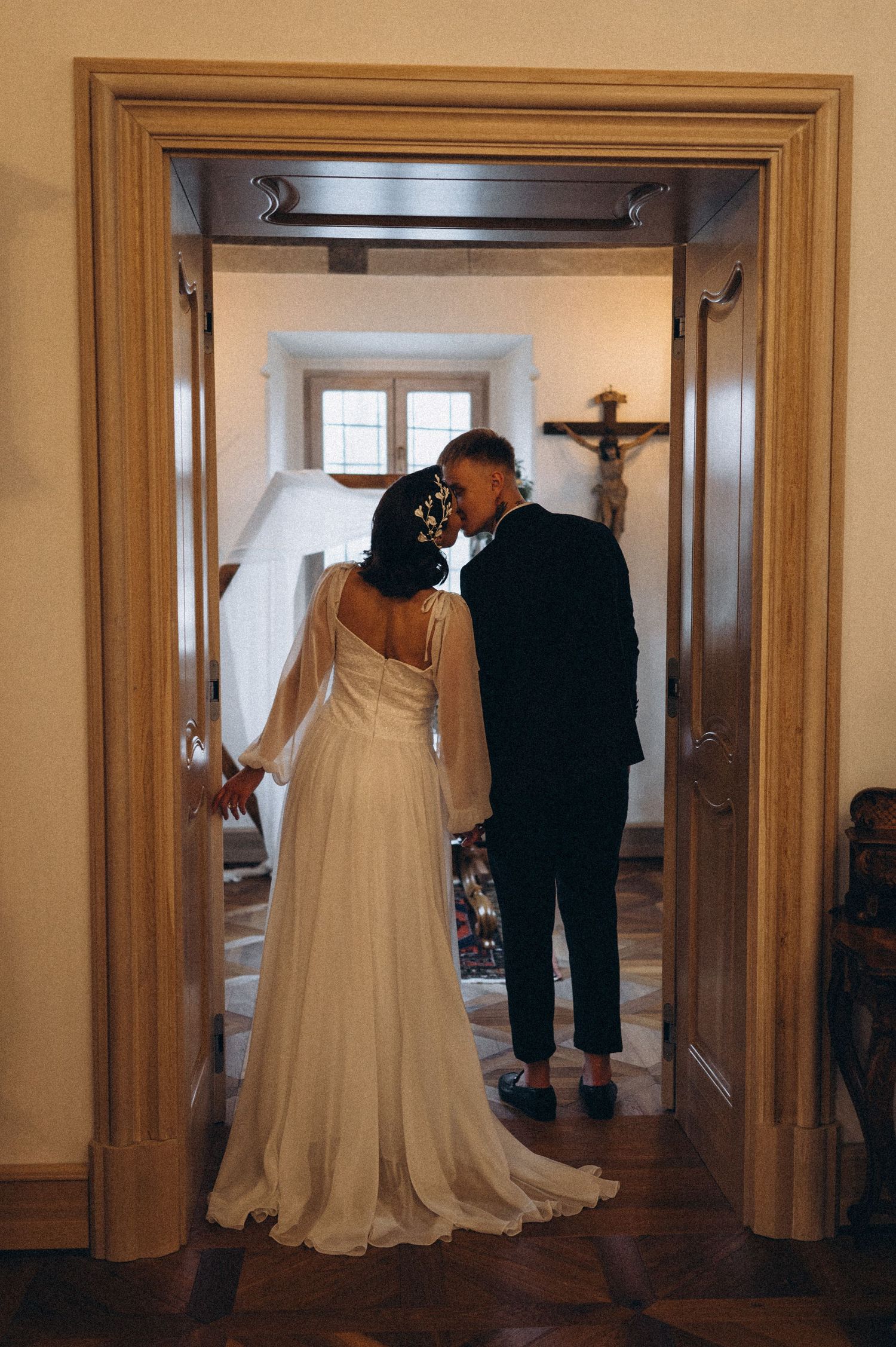 Groom gently kissing the bride’s head as they stand together at the wedding ceremony altar.