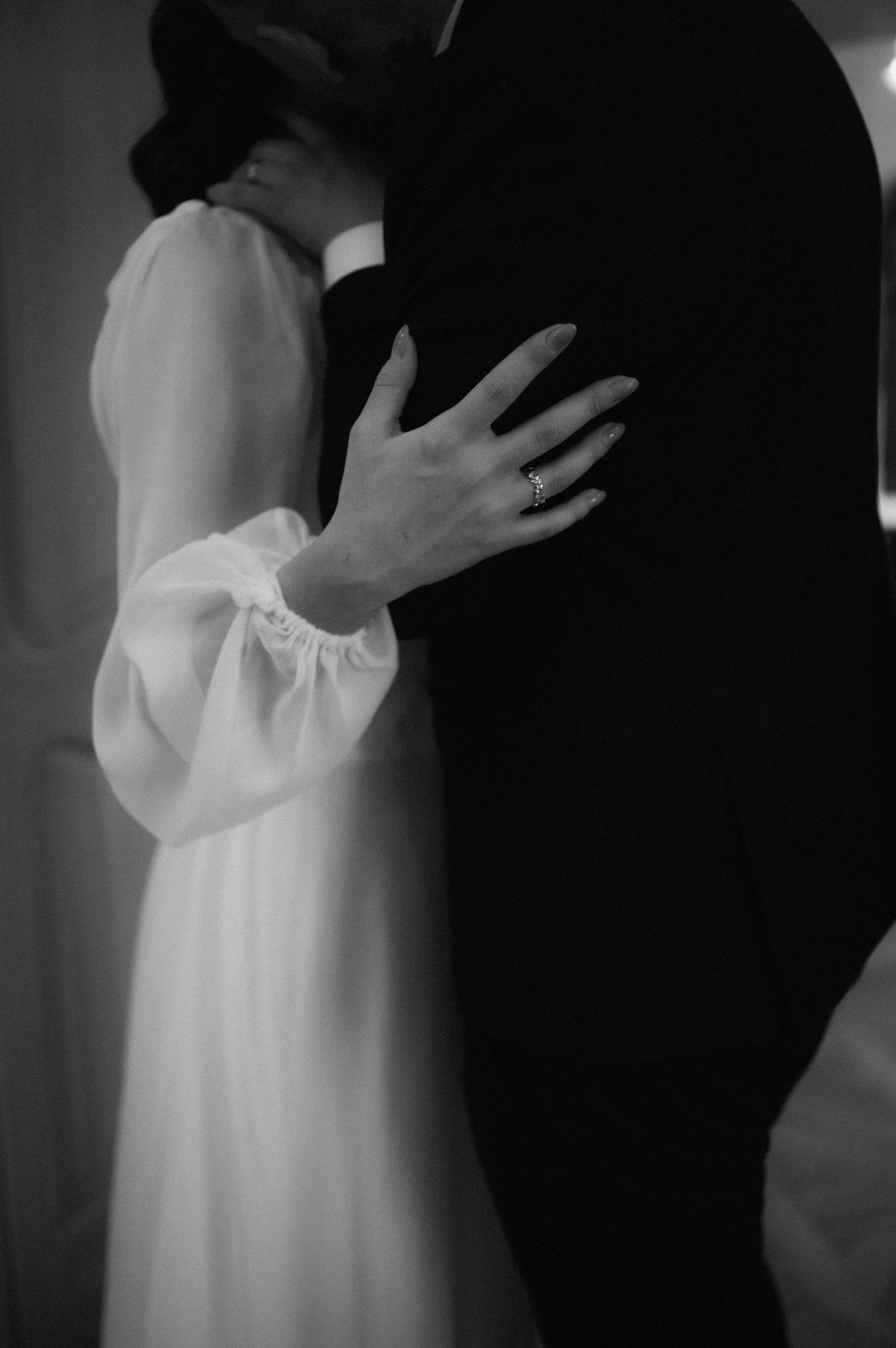 Monochrome detail of the bride holding the groom’s arm as they share a close connection.