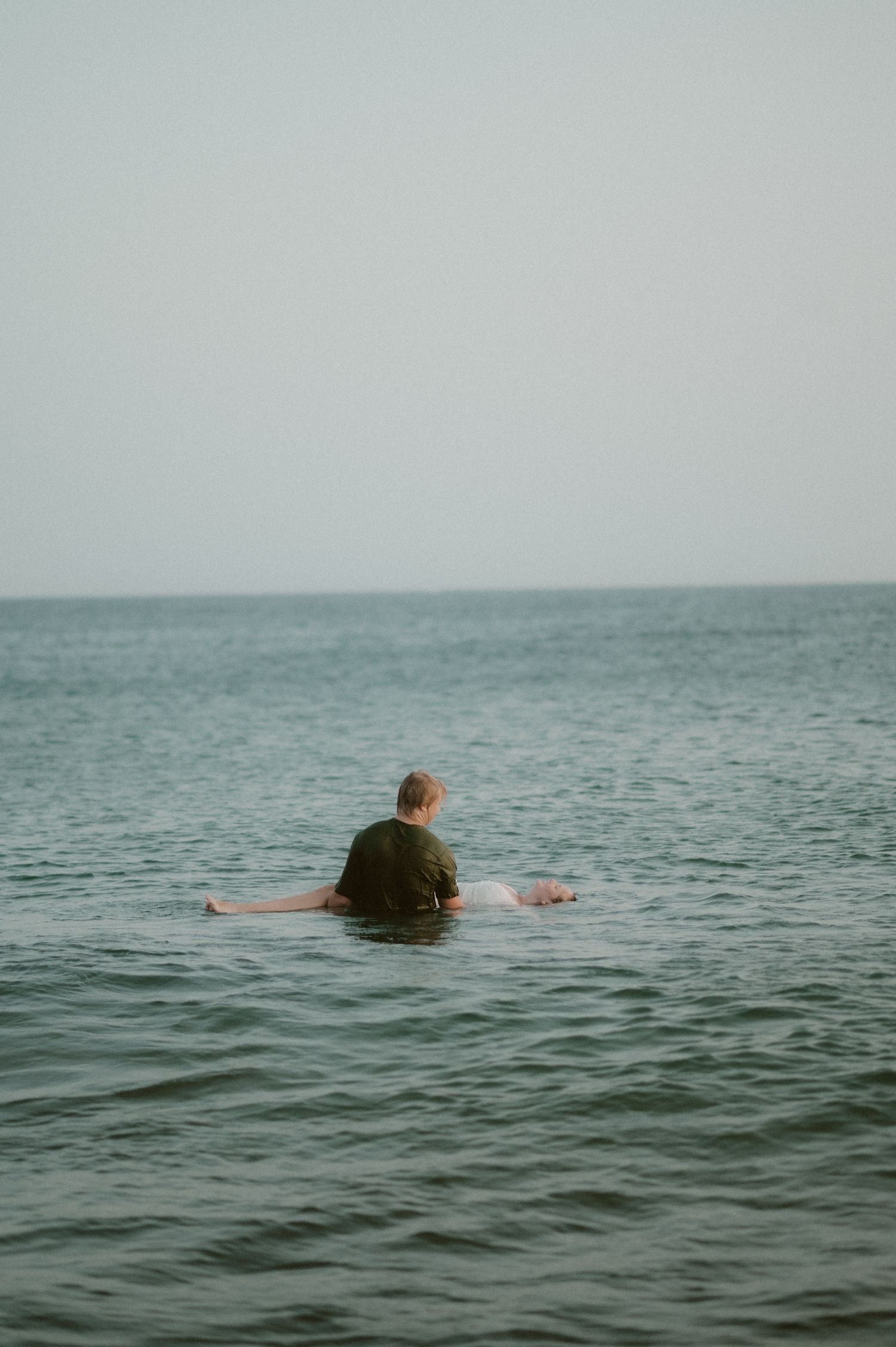 Groom holding his bride in his arms as she floats in the ocean at Playa Tejita, Tenerife couples photography