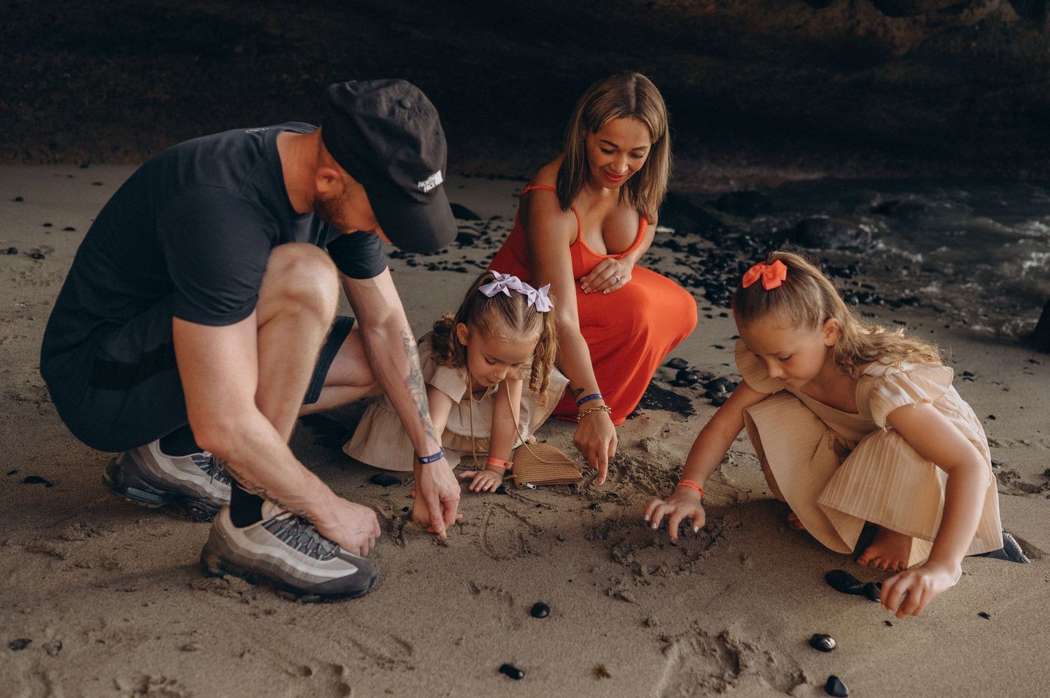 Family enjoying playful sand drawing moments on a Tenerife beach photoshoot