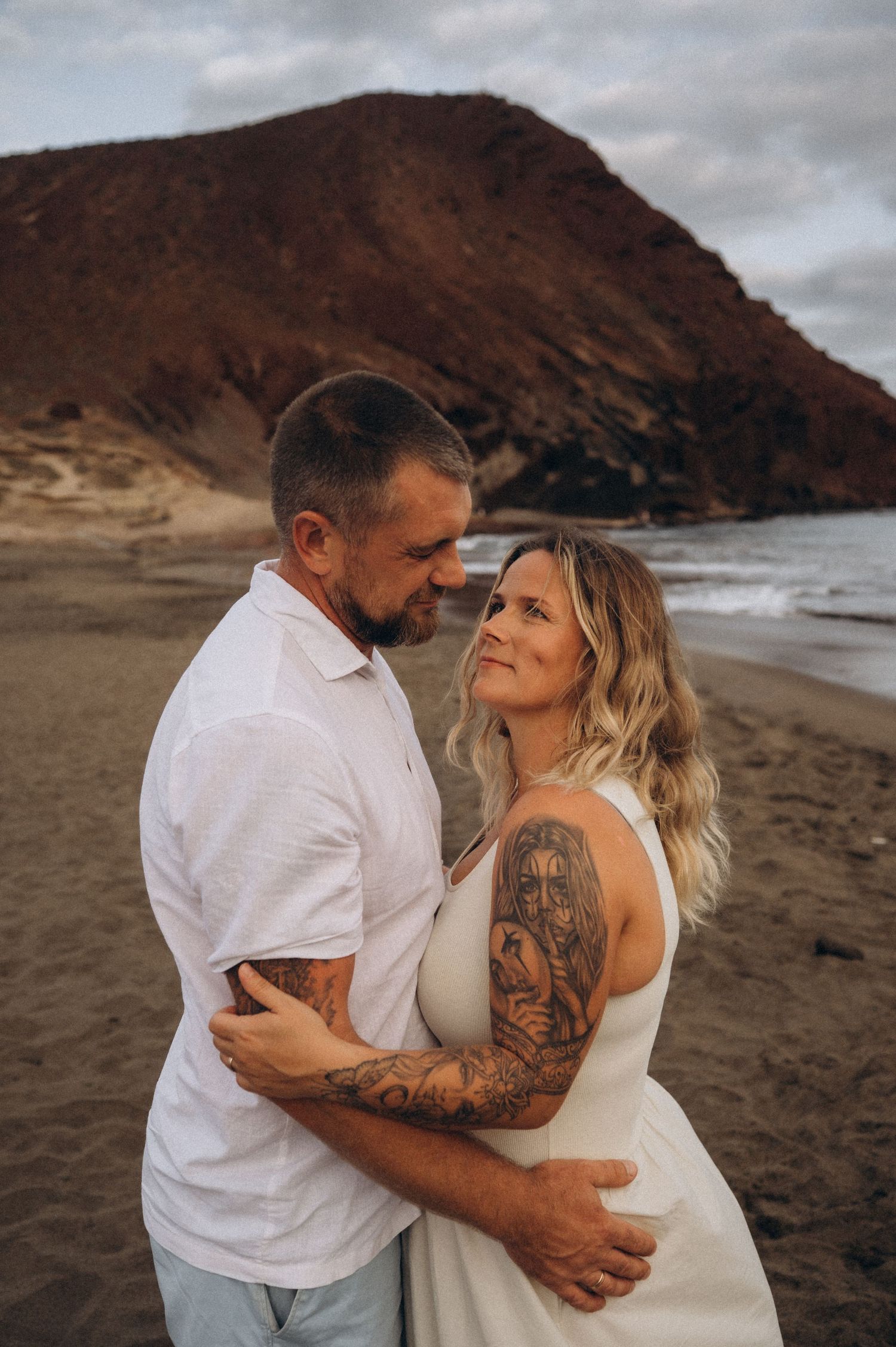 Couple facing each other gazing in love with Montana Roja and ocean behind, Tenerife