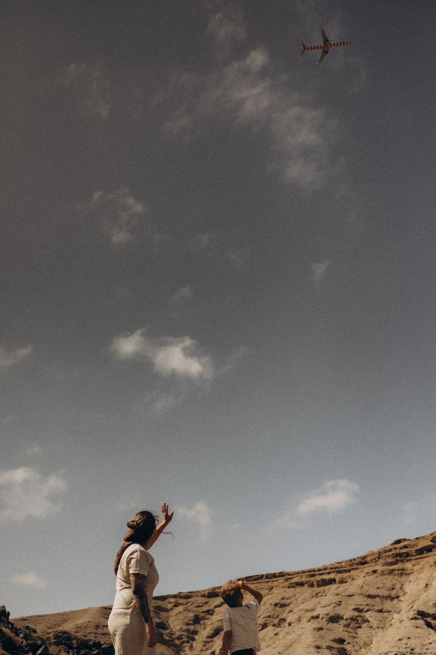 Mom and young son looking at plane flying above Montaña Pelada beach, Tenerife