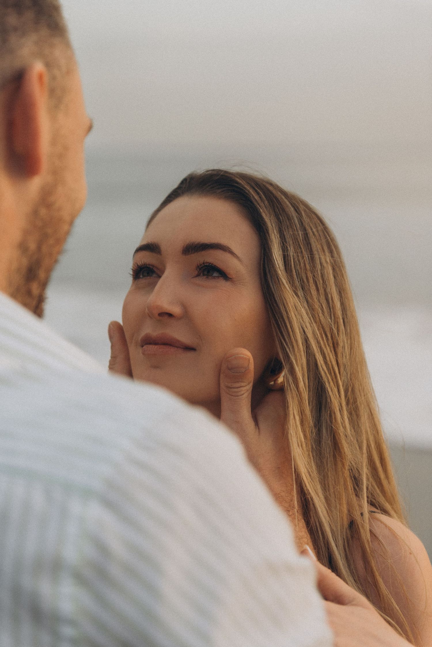 Romantic close-up of her hand with ring around his neck on Playa de La Tejita, Tenerife