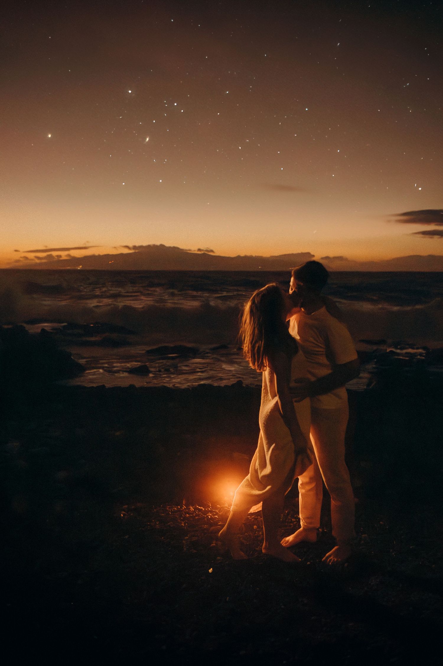 Face-to-face couple in romantic moment on south Tenerife beach with night lighting, Tenerife