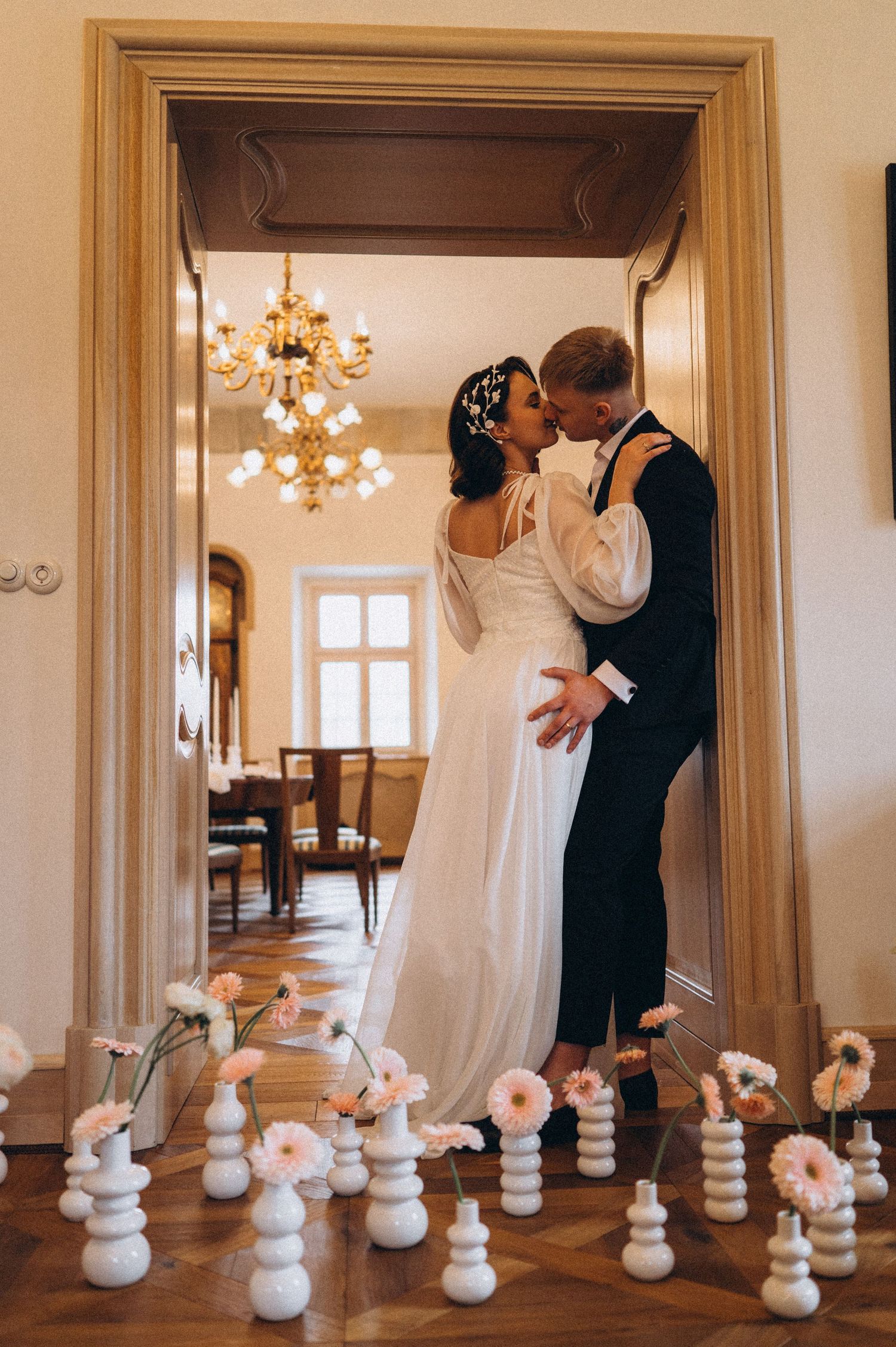 Romantic couple portrait in a castle doorway with the groom leaning on the frame and candles illuminating the scene.