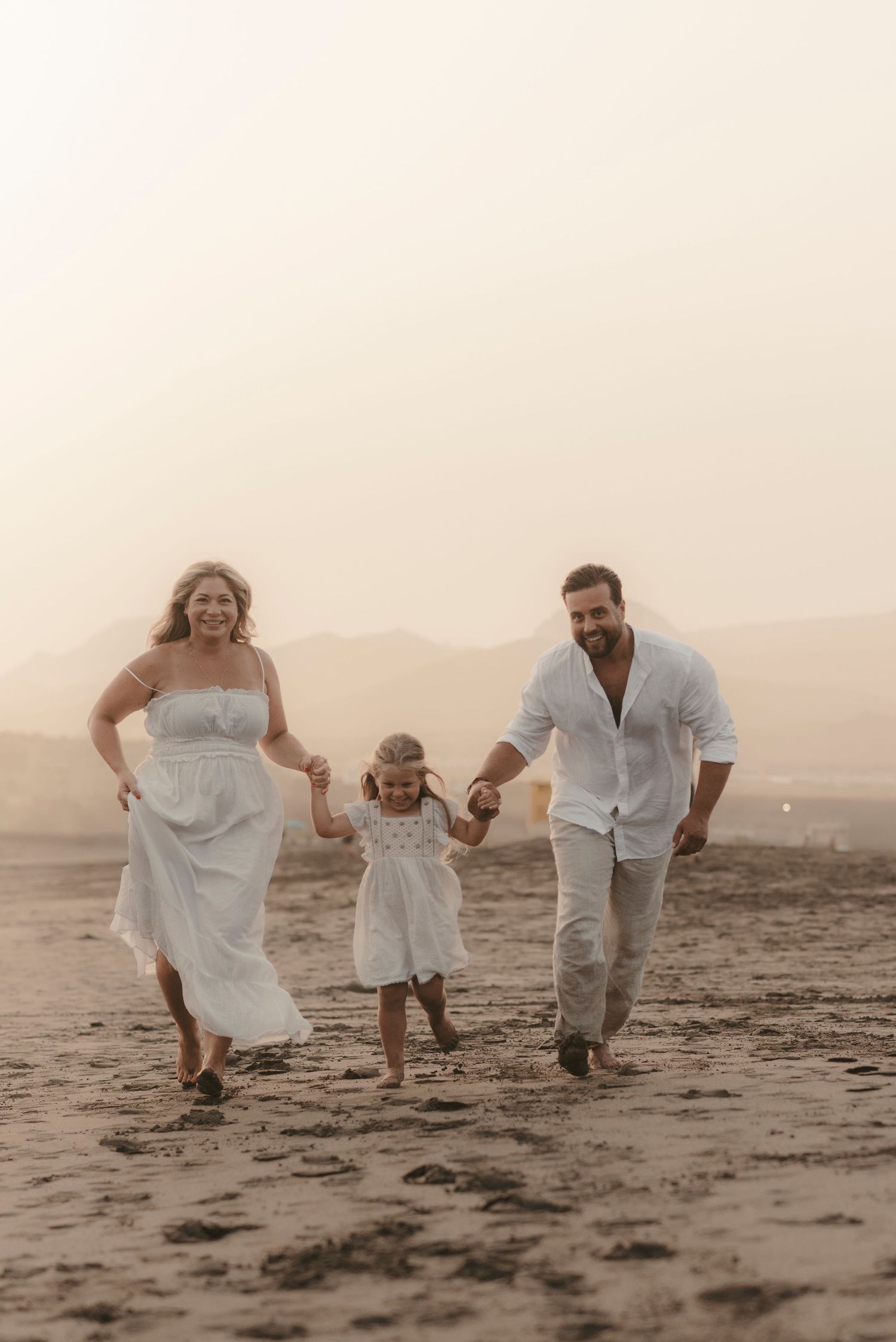 Family walking hand in hand along the sandy Playa La Tejita beach in Tenerife during a golden hour family photoshoot, storytelling family ph