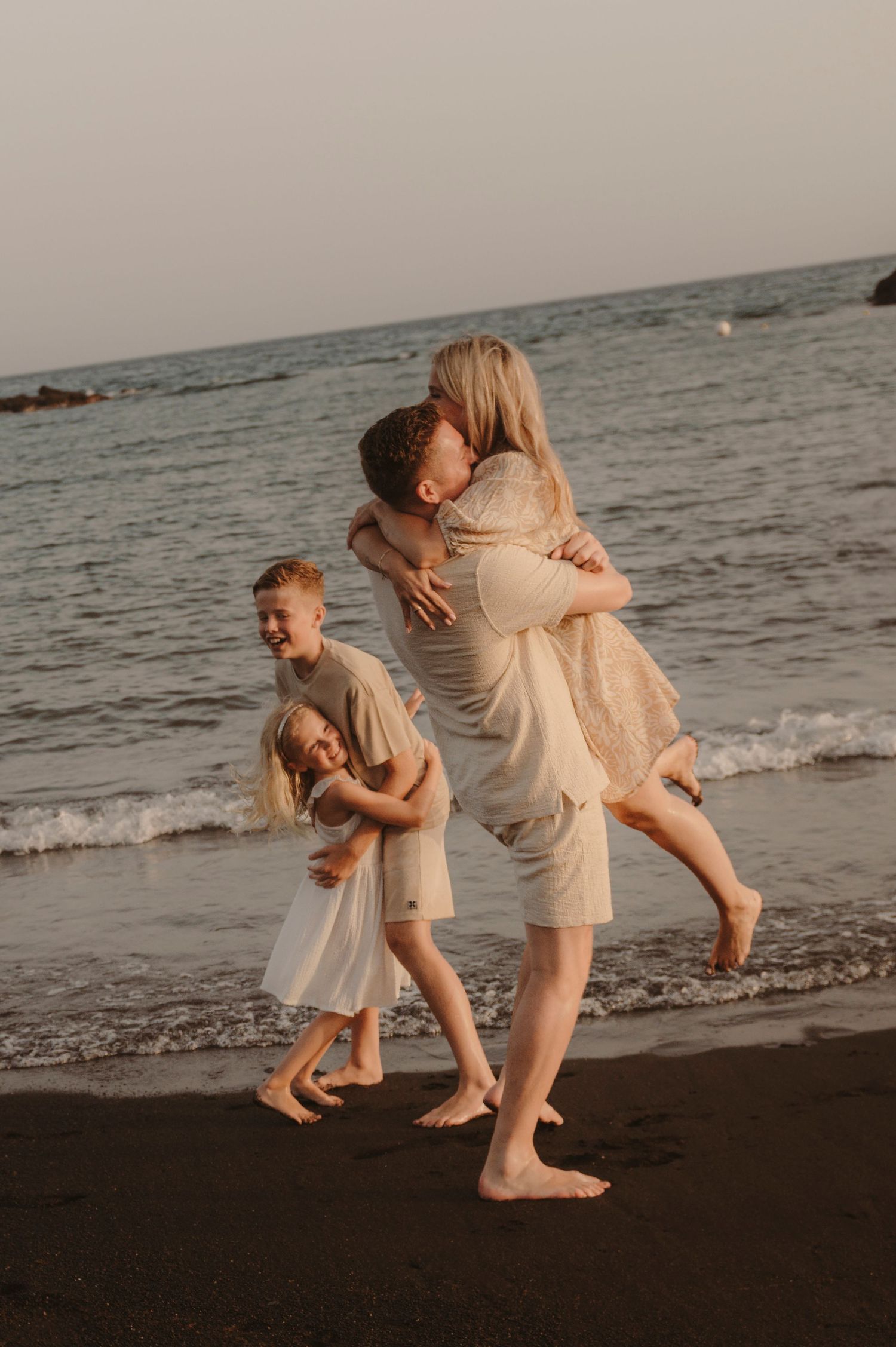 Family enjoying playful moment on beach at sunset, Tenerife