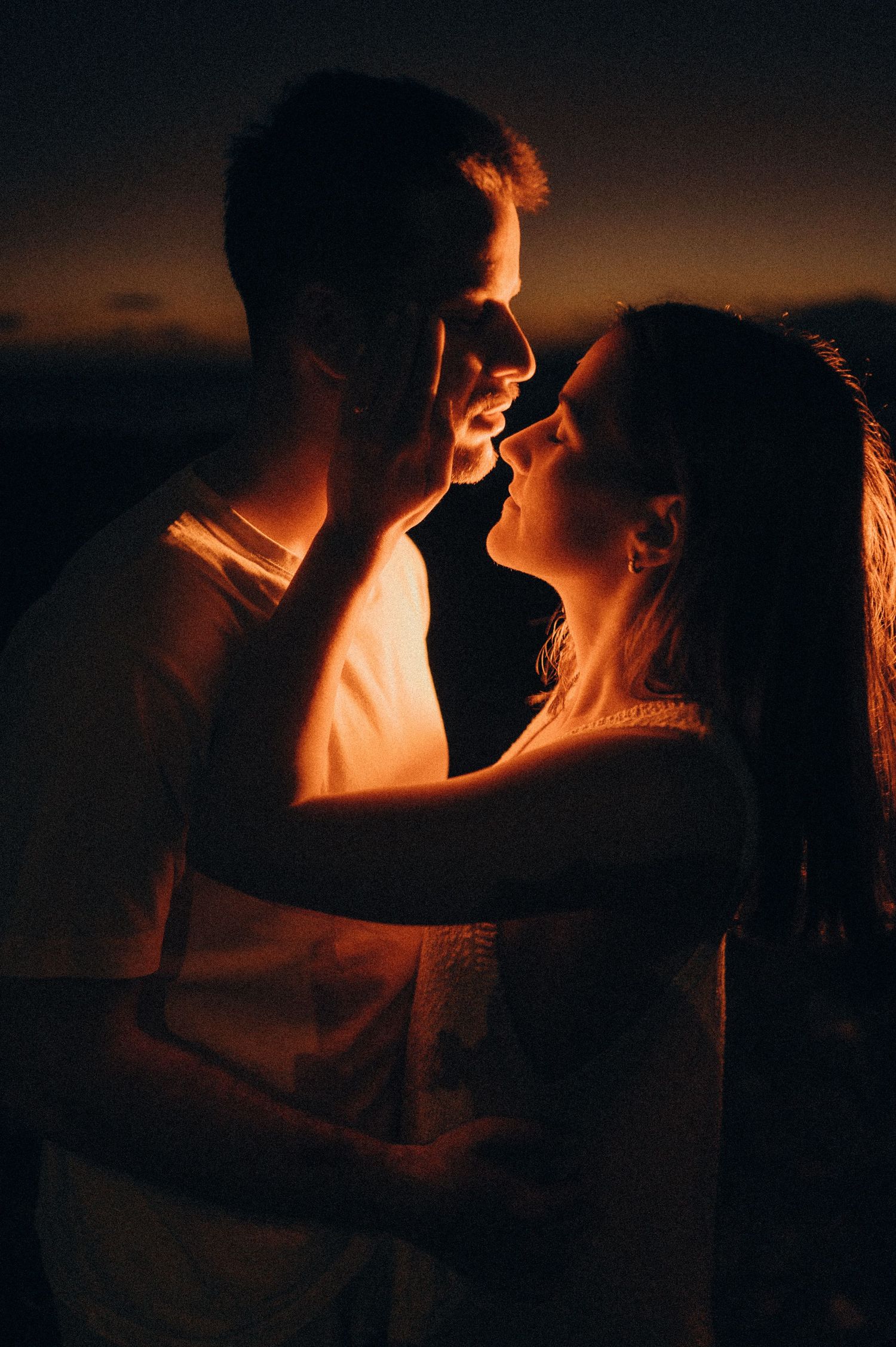 Young couple standing face-to-face, gazing into each other’s eyes on south Tenerife beach at night