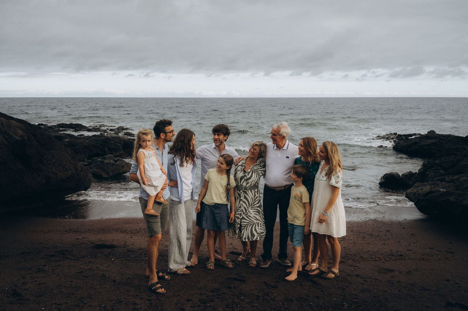 Family of all ages strolling from the ocean along black beach toward the camera at Los Refugios