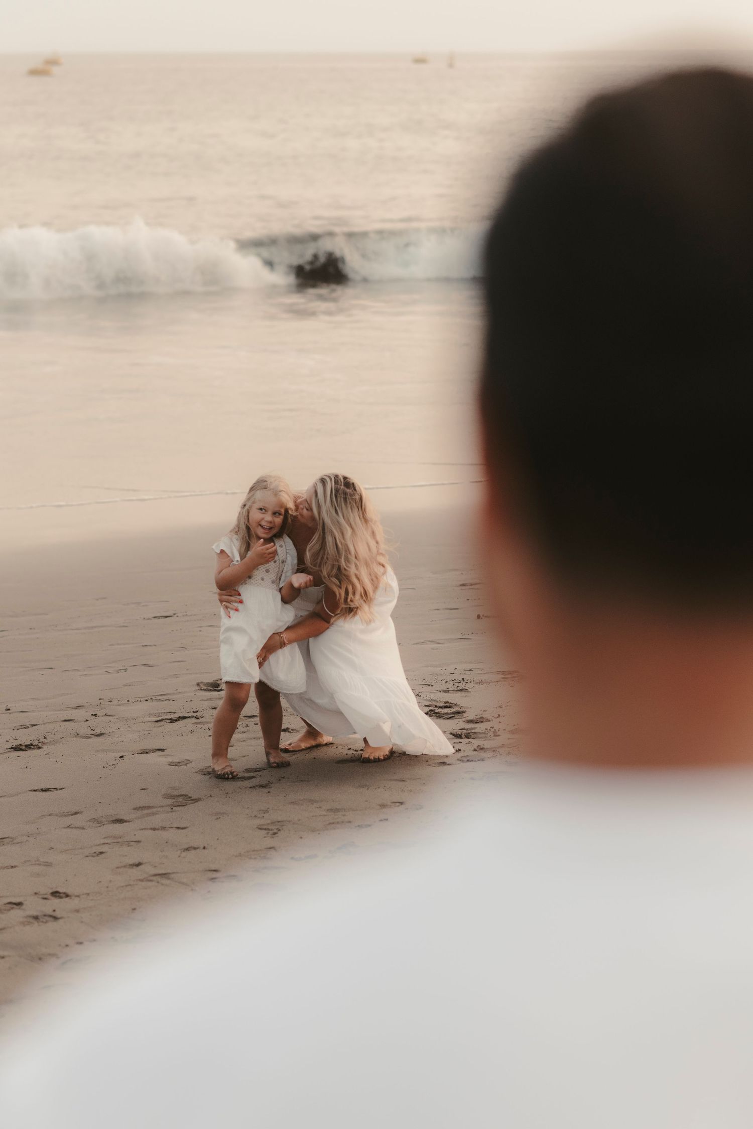 Father observing his wife and daughter enjoying the beach together on Playa La Tejita with ocean behind them