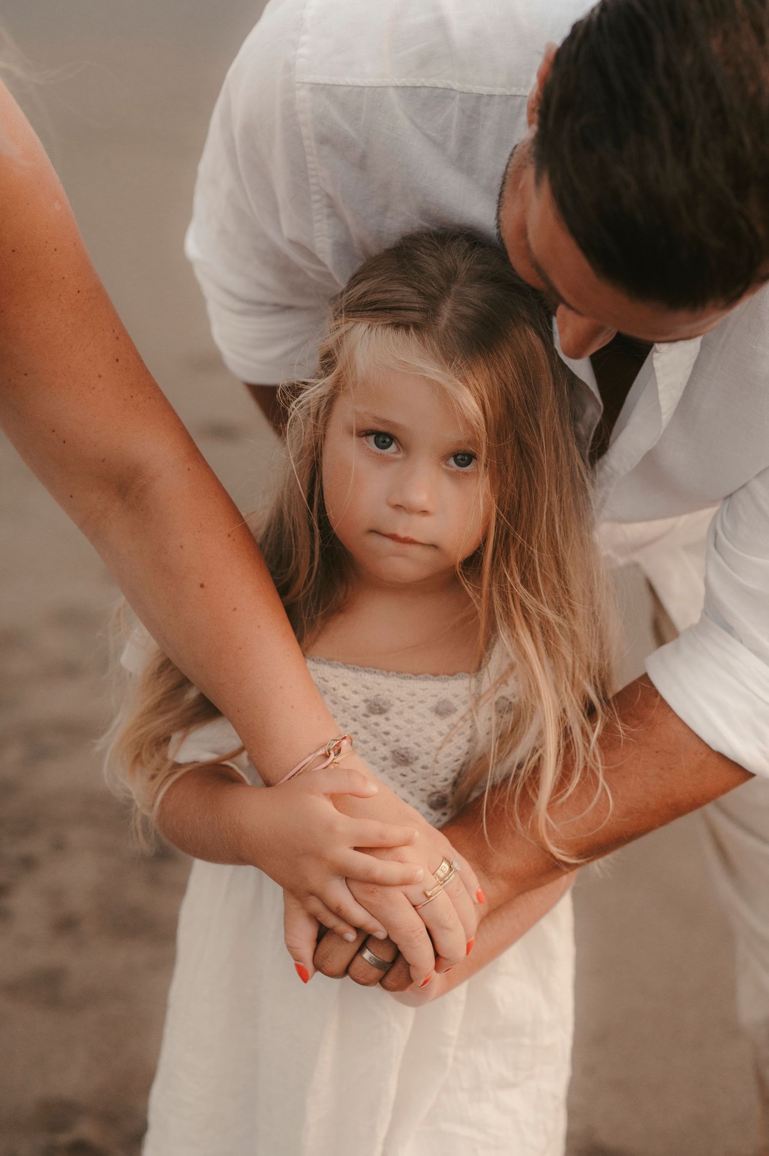 Tender moment of father kissing his daughter’s head as she looks into the camera, emotional family photography