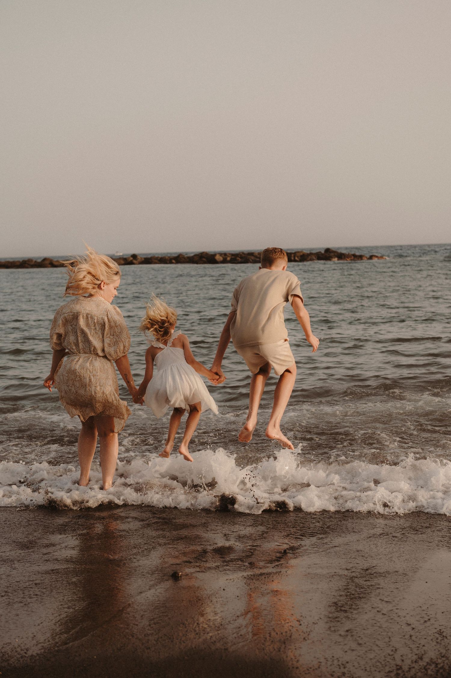 Joyful moment with whole family jumping into waves on vulcano beach, Tenerife