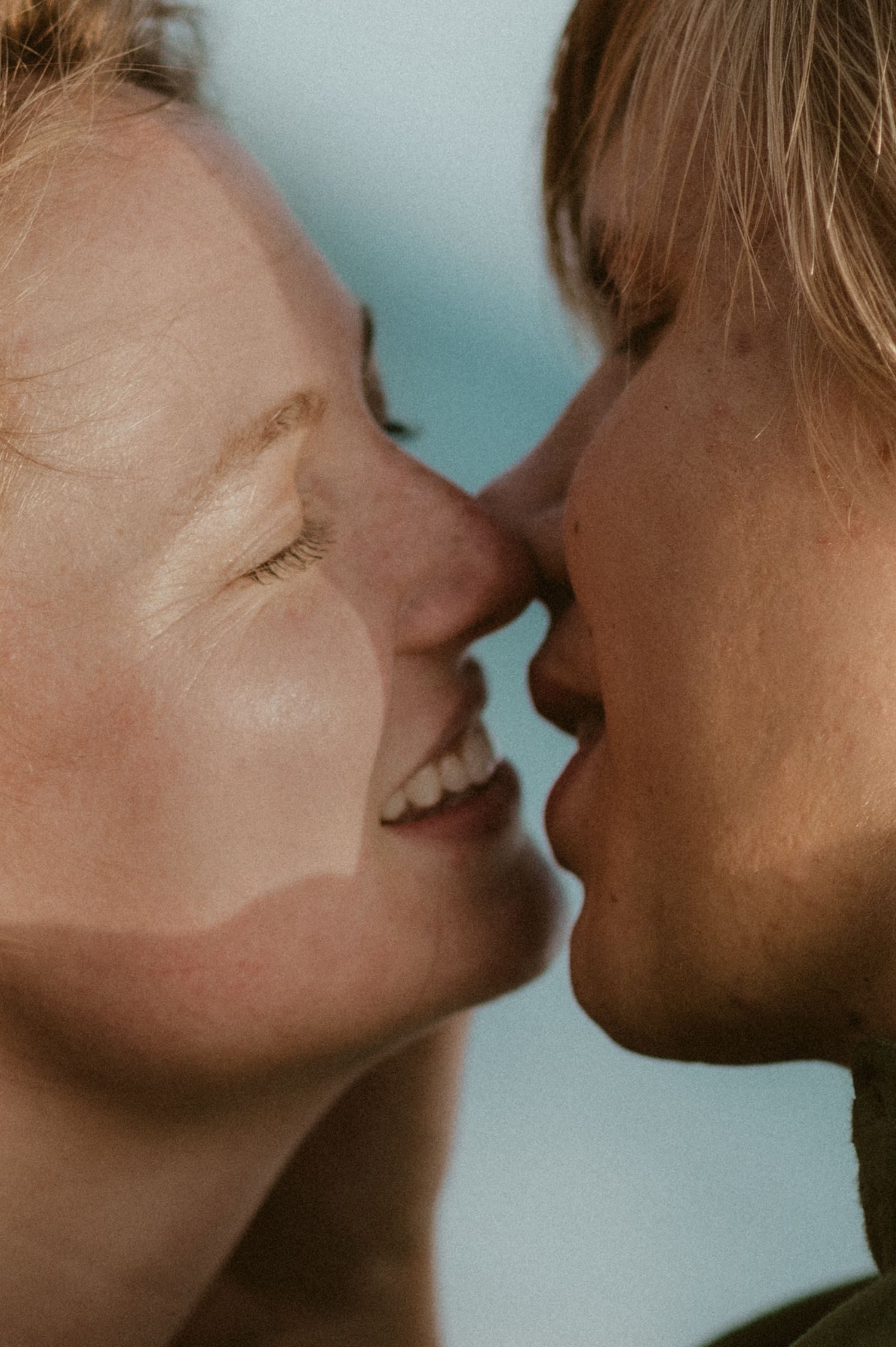 Close-up of a young couple kissing with the ocean softly visible in the background at Playa Tejita, Tenerife couples photoshoot