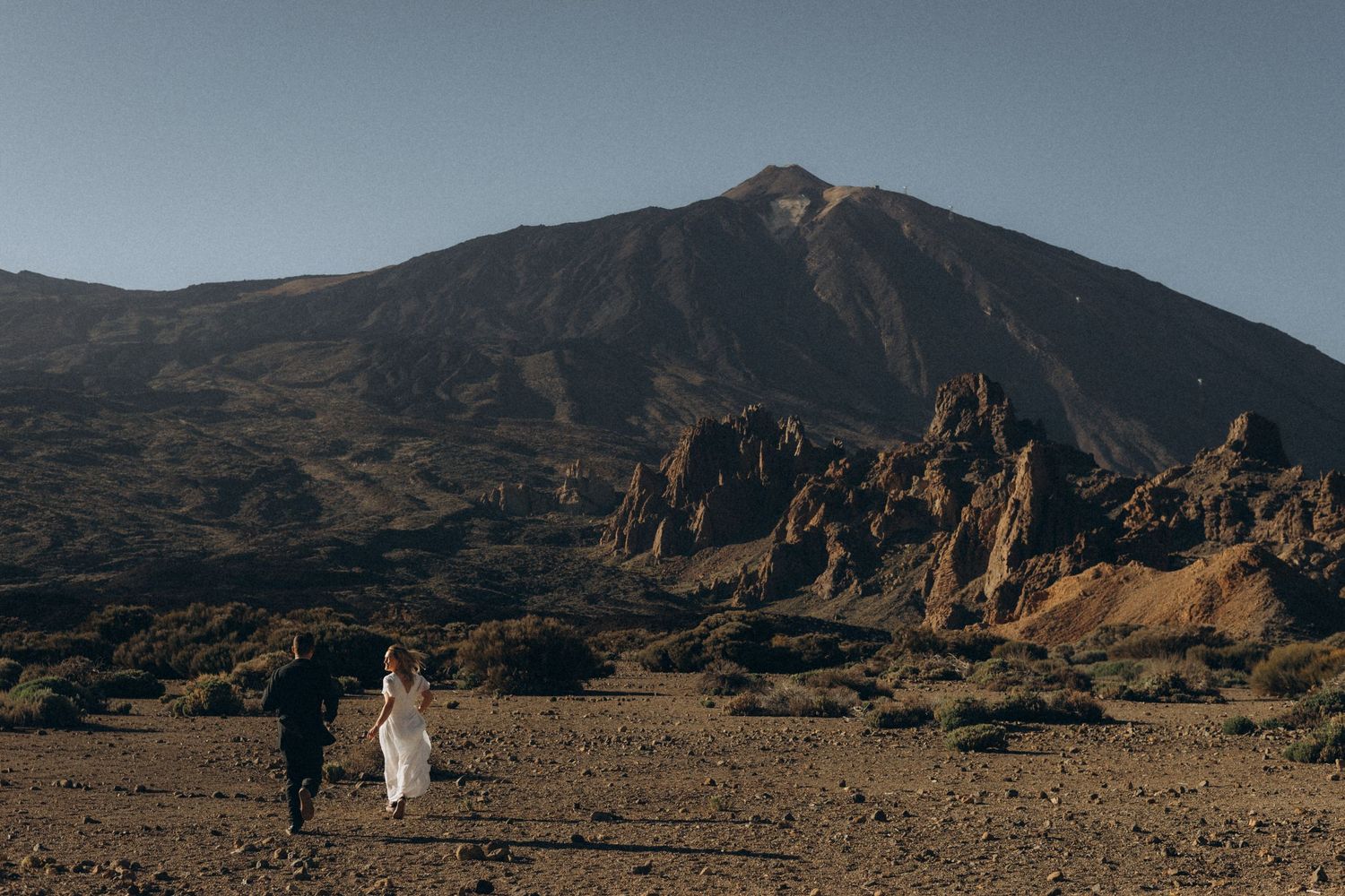 Couple walking through volcanic landscape with Mount Teide in background, Tenerife elopement photography.