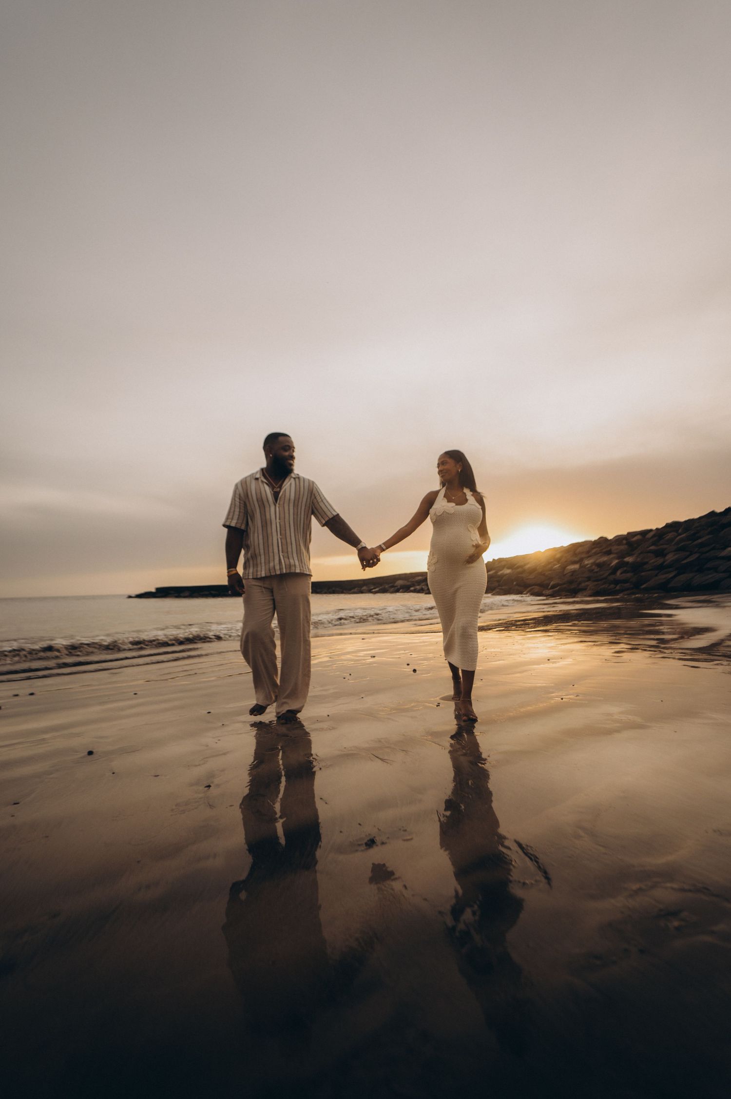 Romantic pair strolling along beach with mirrored reflections at sunset, Playa Fañabé