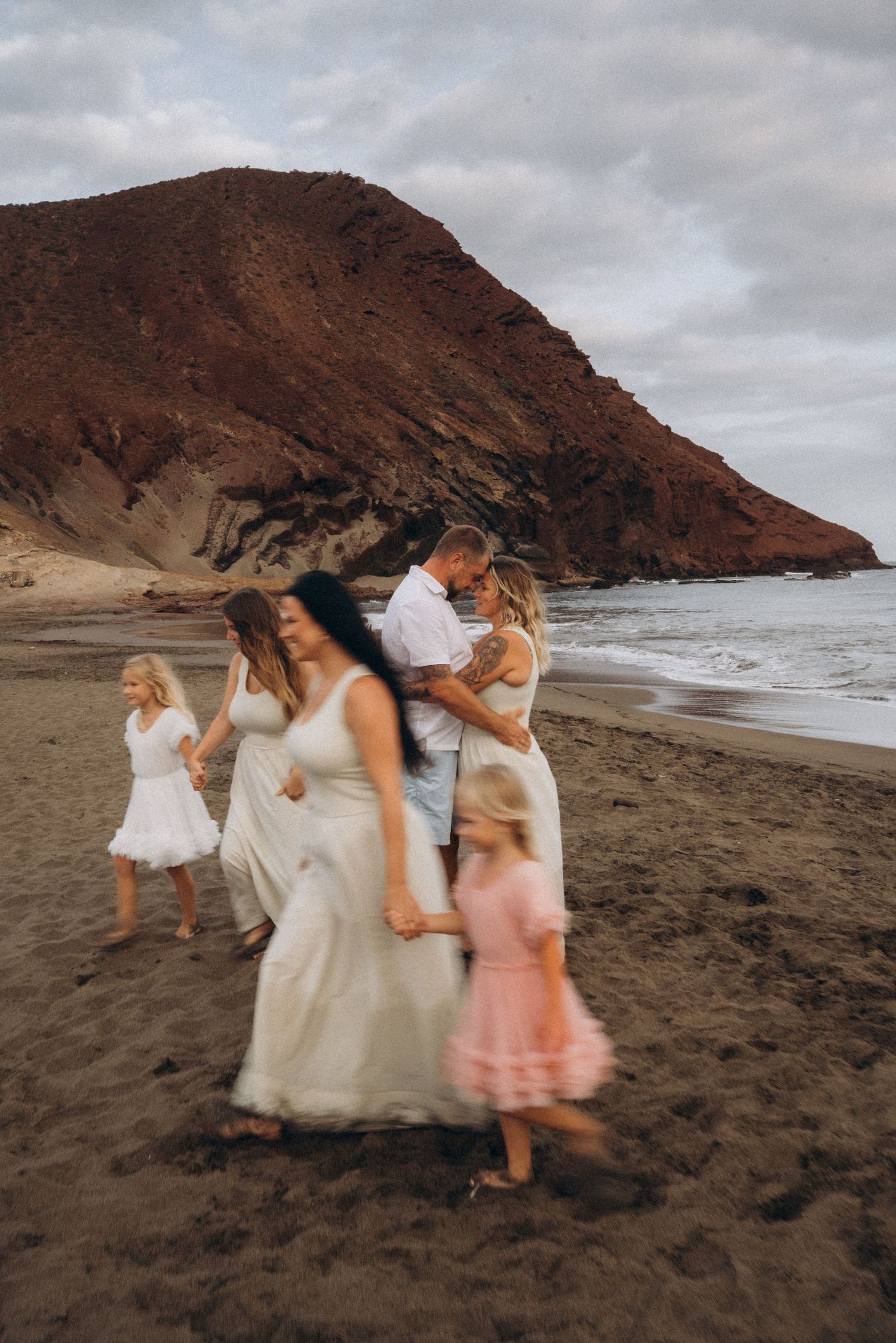 Married couple embracing surrounded by entire family on Playa La Tejita, Tenerife